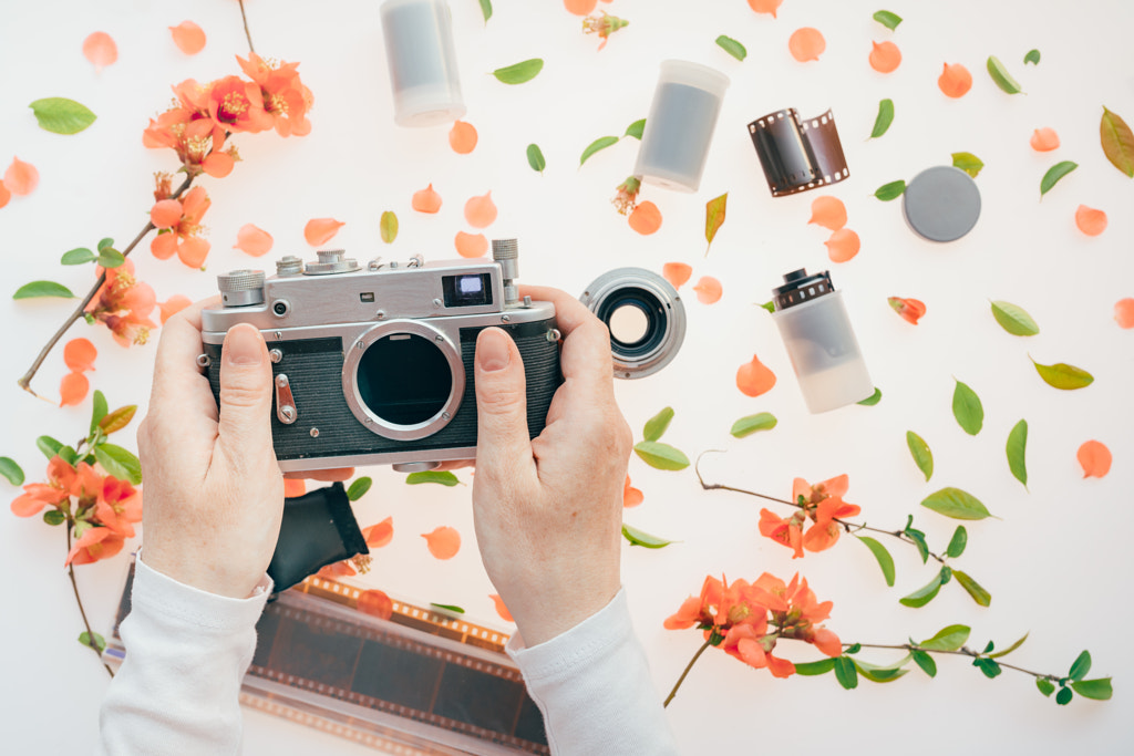 Woman holding vintage camera over springtime floral decoration by Igor Stevanovic on 500px.com