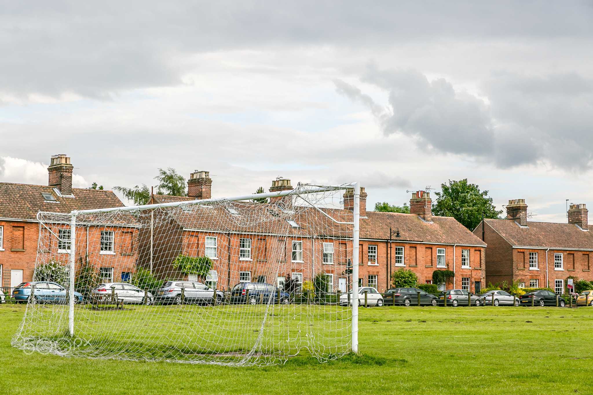 Football goal in a field in the city of Norwich with houses in t