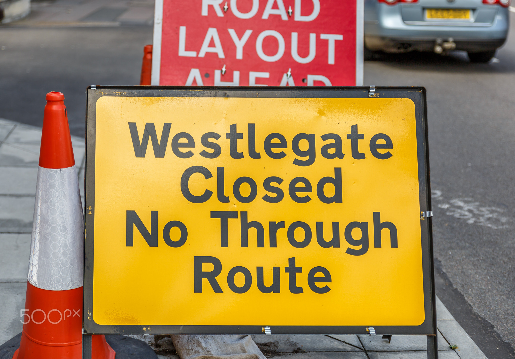 Yellow sign in the middle of an English street, indicating that