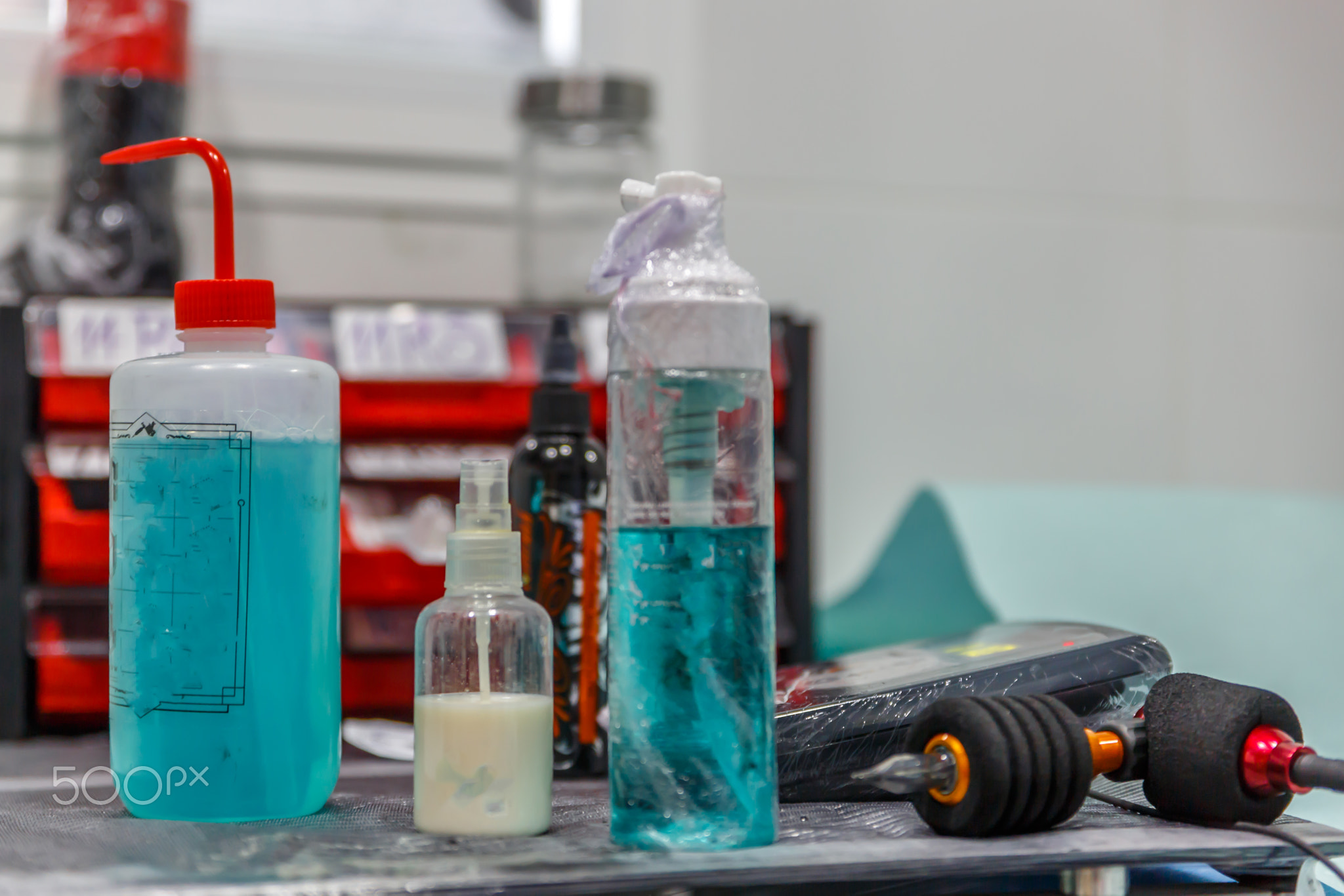 Close-up of a tattoo machine, next to bottles and other instrume