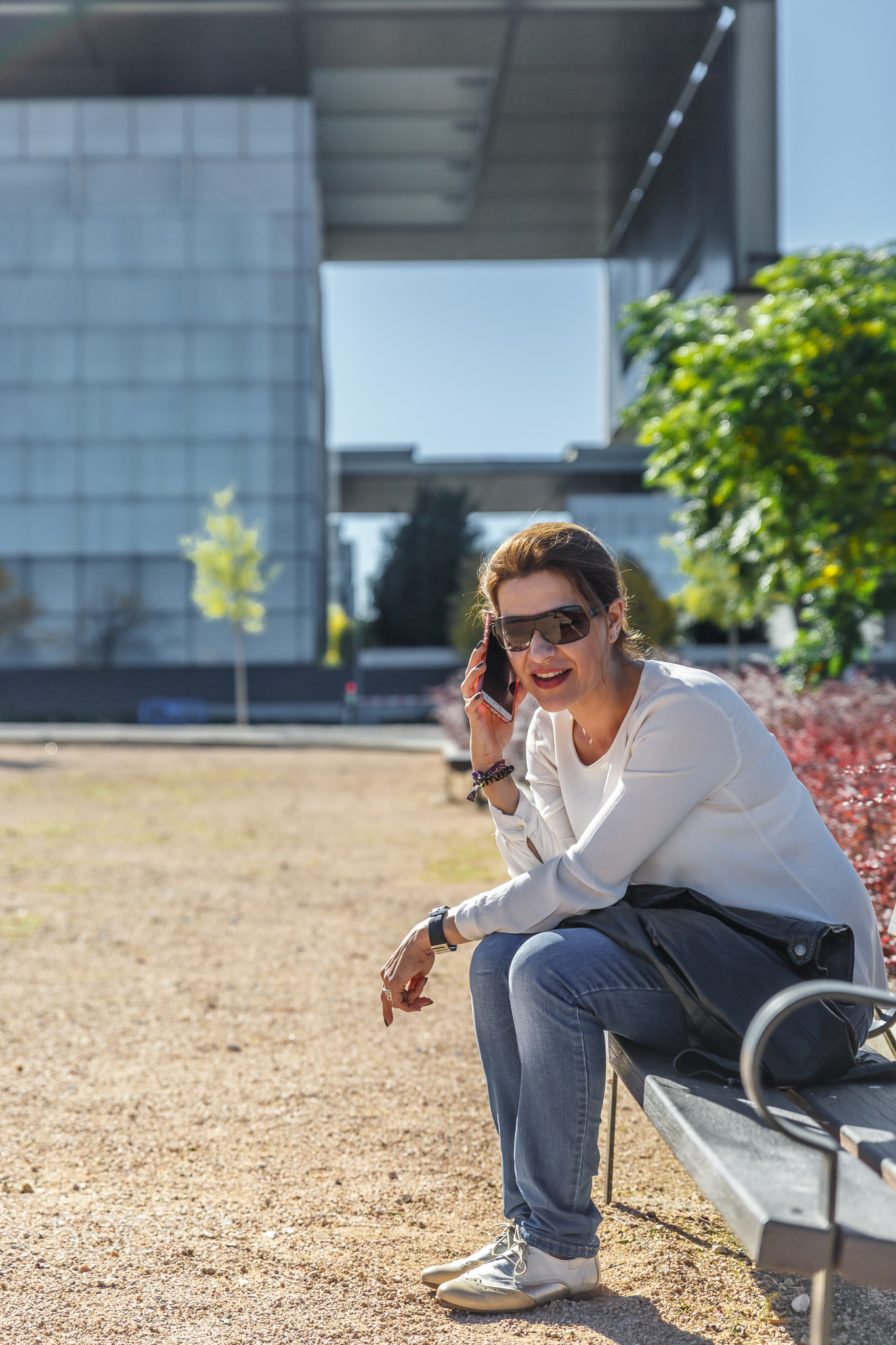 A woman smiles while talking on mobile phone, sitting on the ben