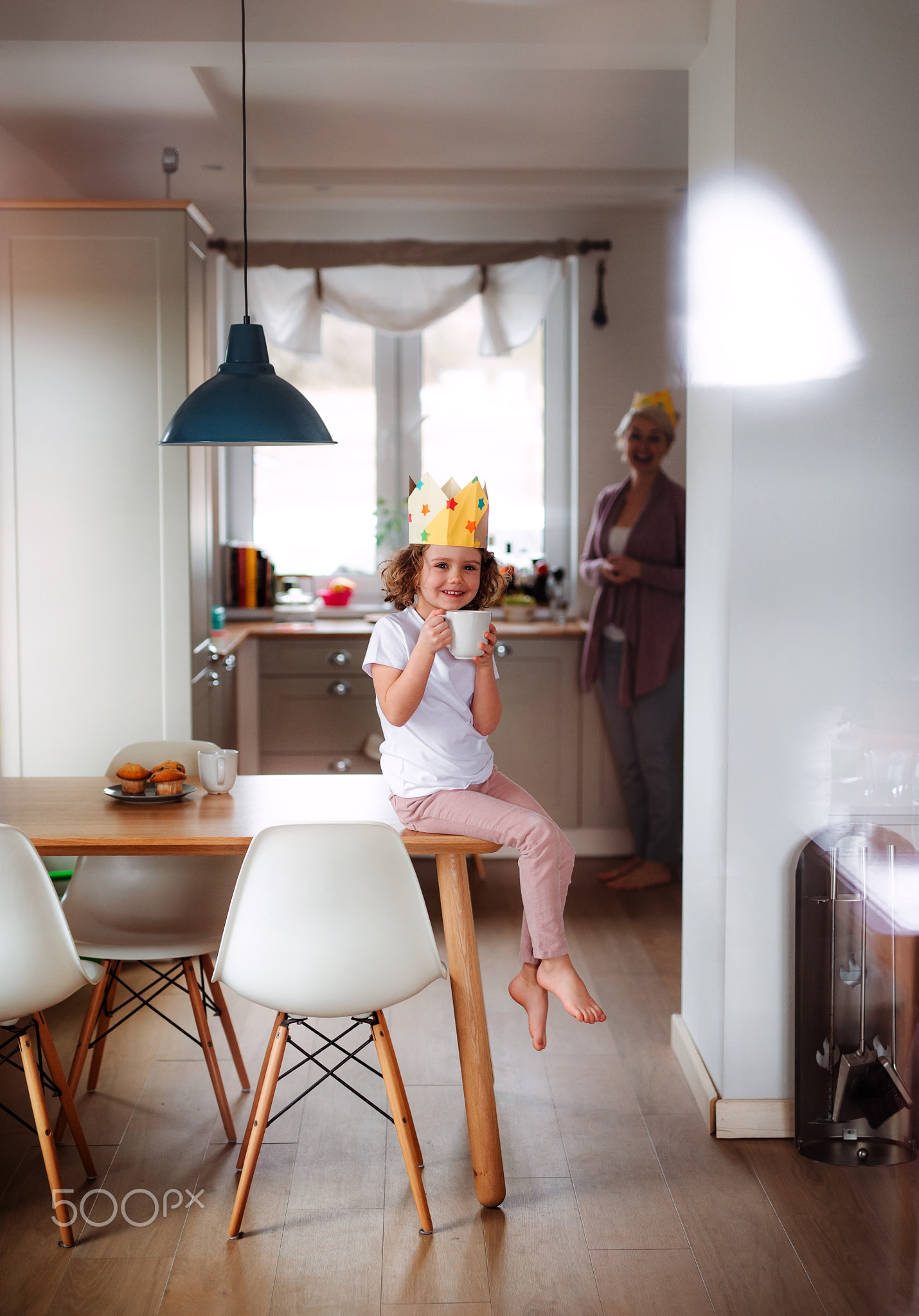 A portrait of small girl and mother with paper crown at home.
