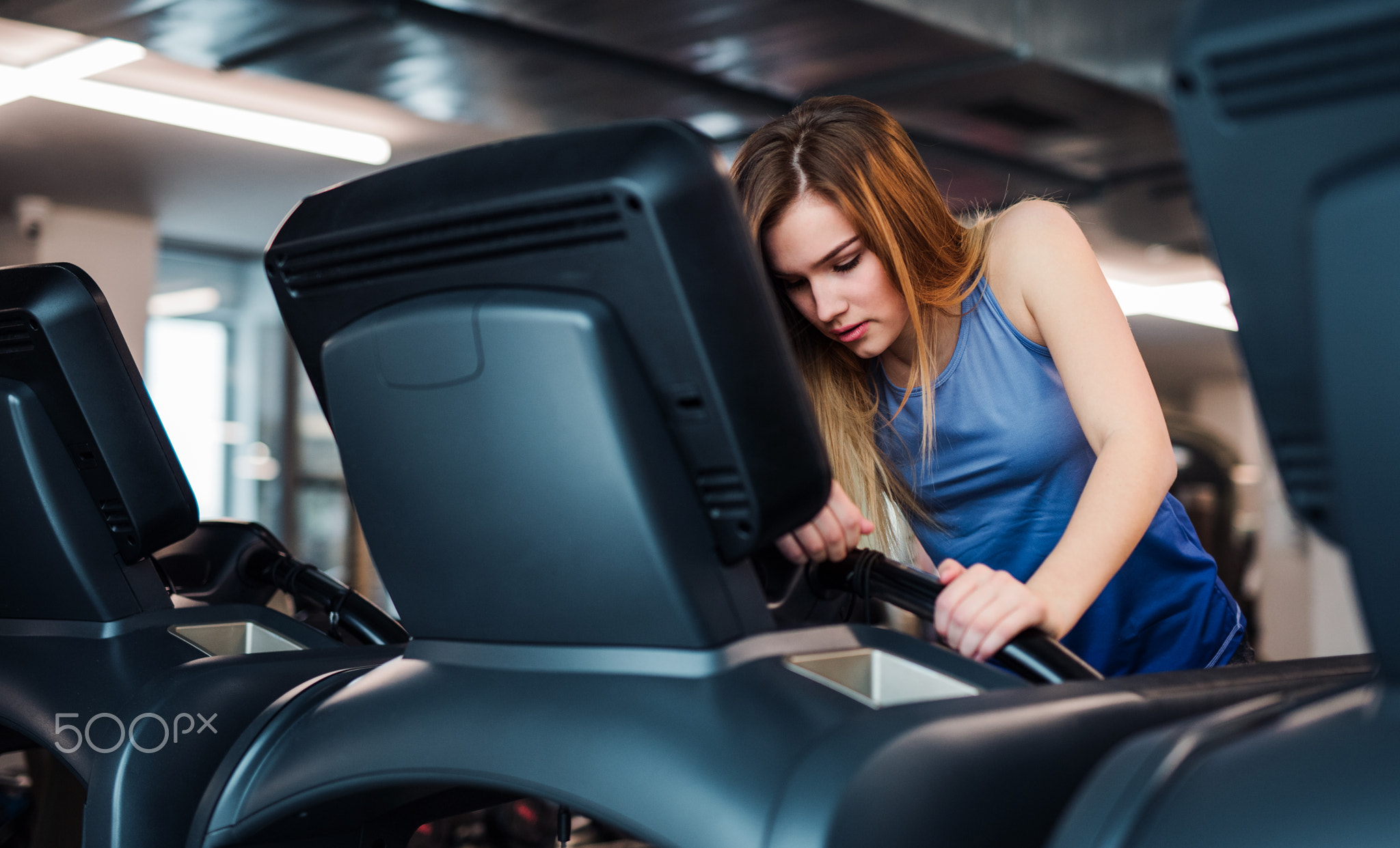 A young girl or woman doing cardio workout in a gym.