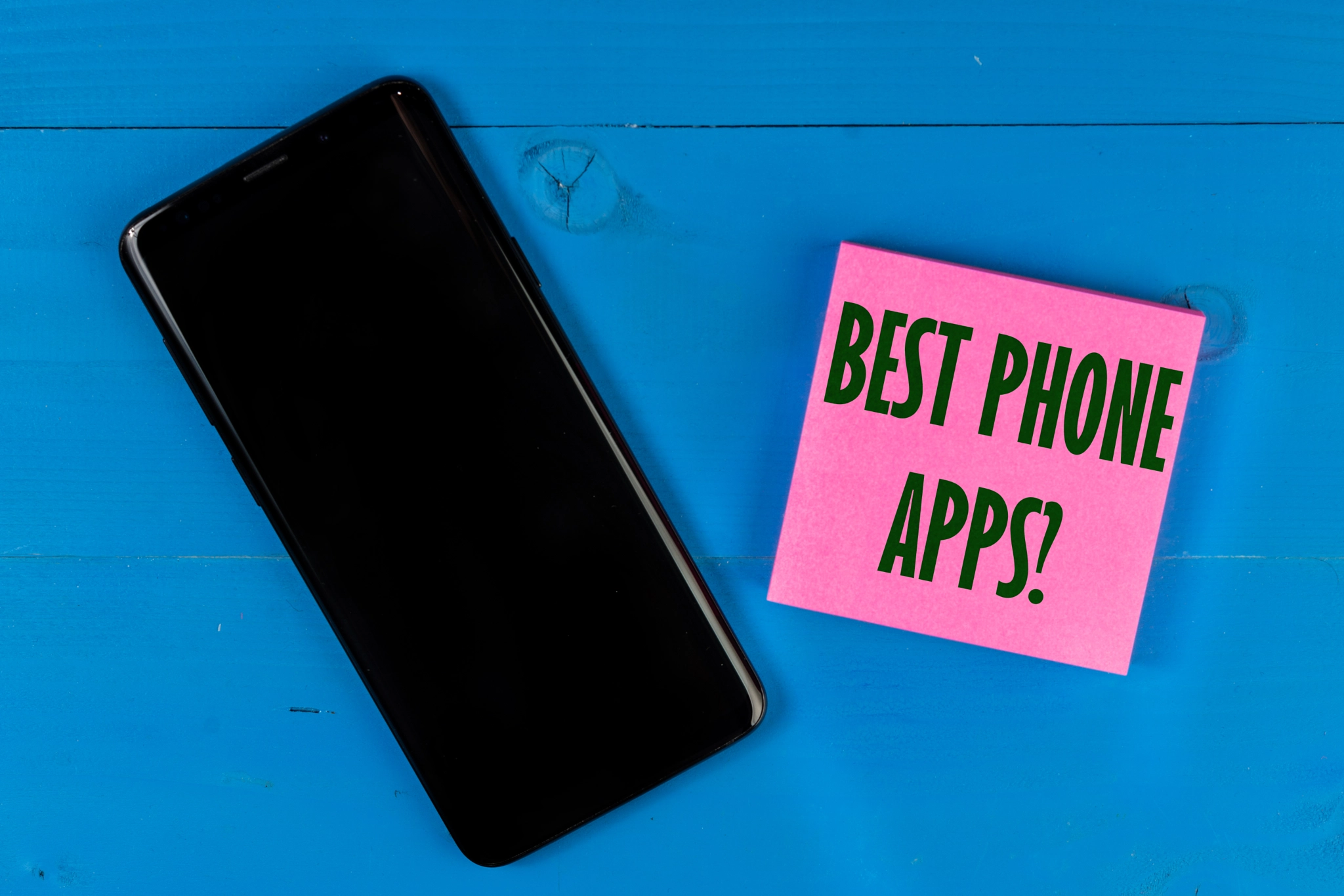 Best Phone Apps concept on block paper. Black mobile phone with empty black screen for copy space.