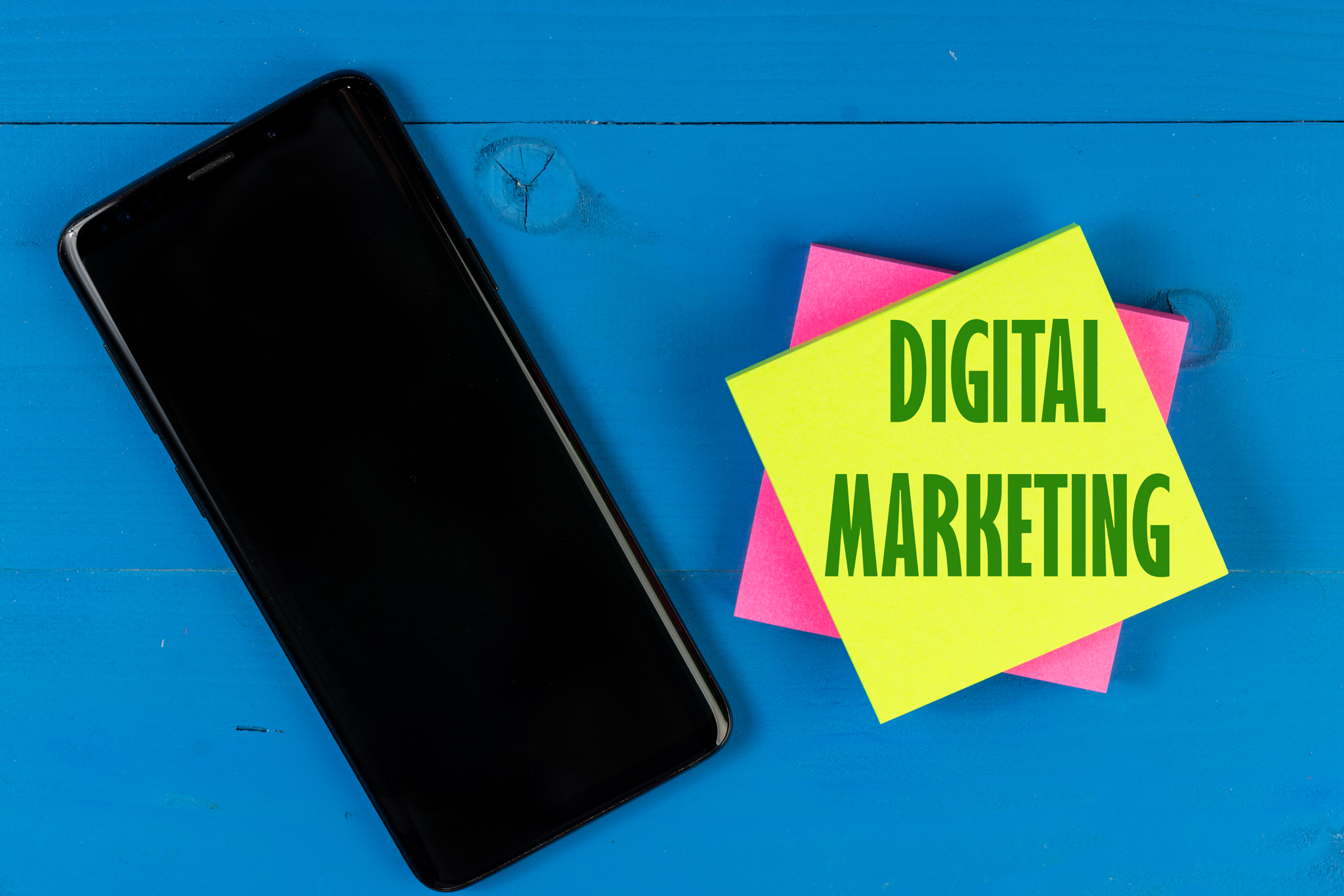 Digital Marketing text concept on block paper. Black mobile phone with empty black screen for...