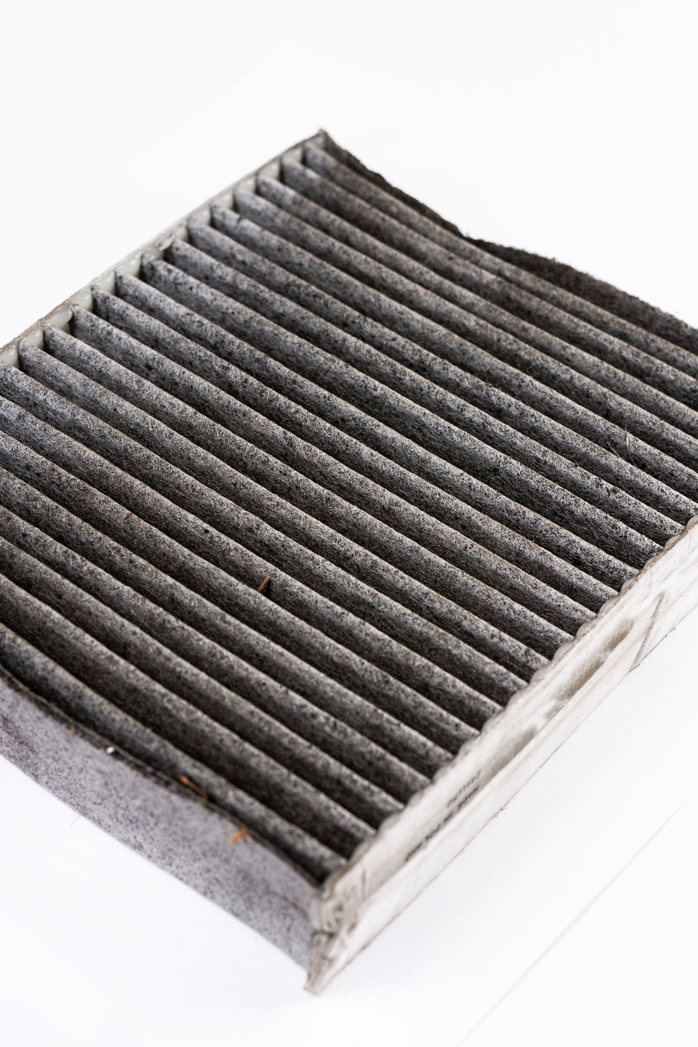 Dirty used car air conditioner filter isolated above white background.