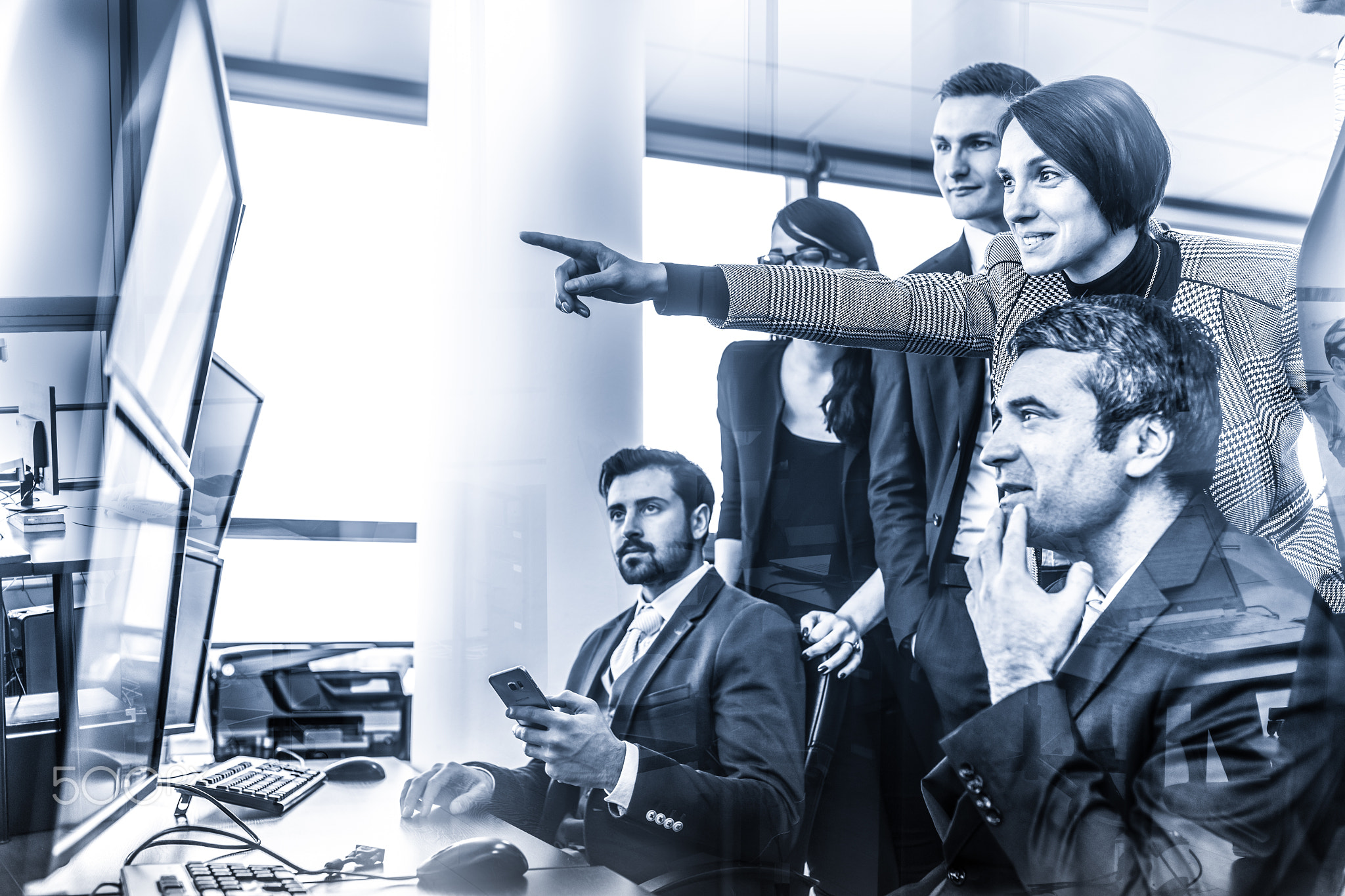 Successful business team looking at trade data on computer screens in corporate office.