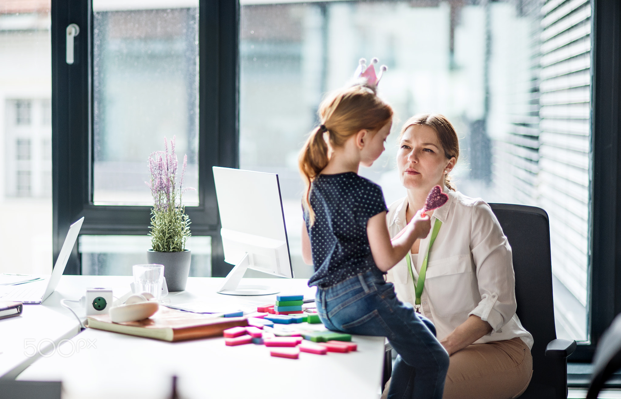 A businesswoman with small daughter sitting in an office, working.