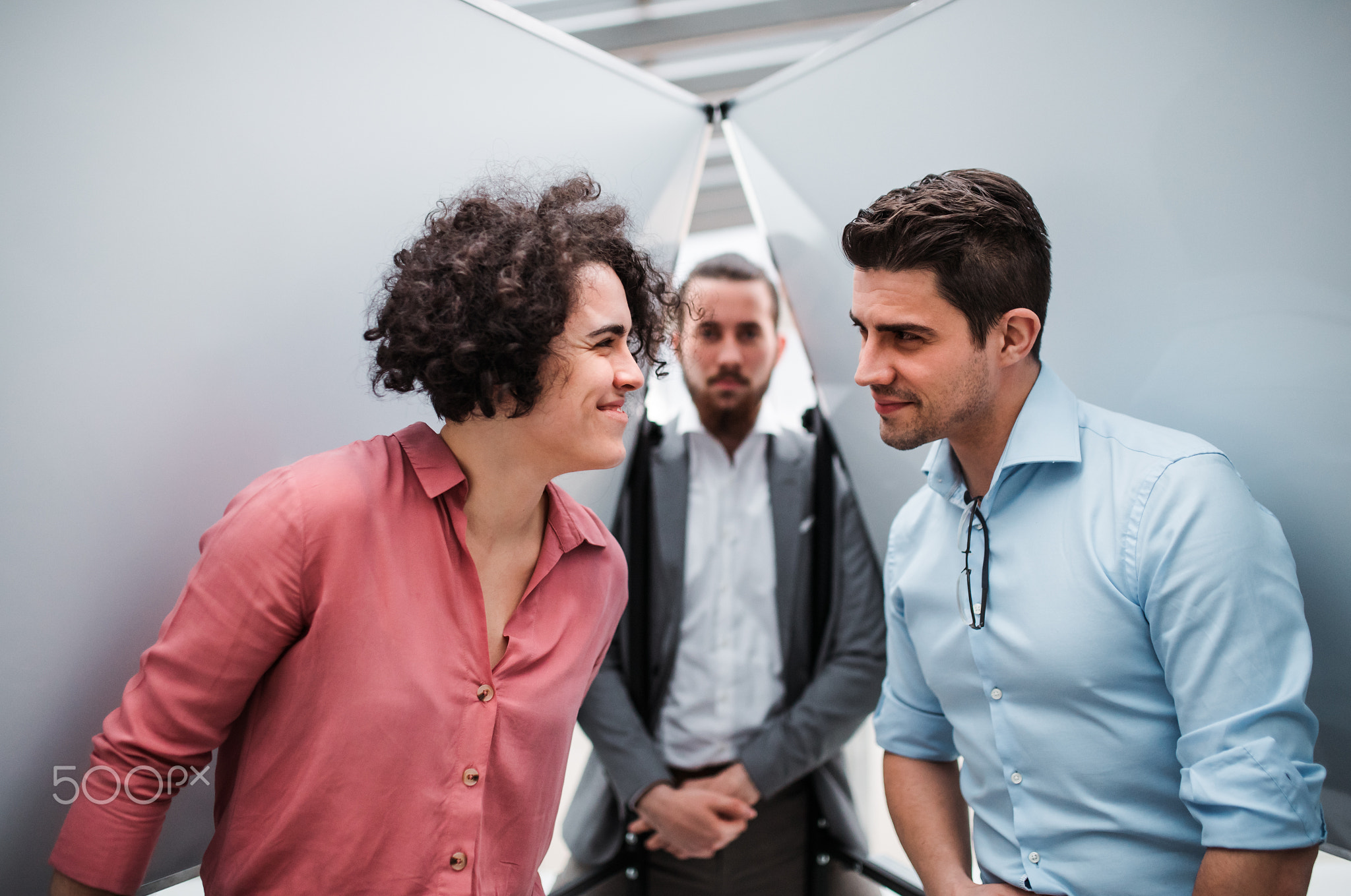 Young businesspeople standing in office, having fun.