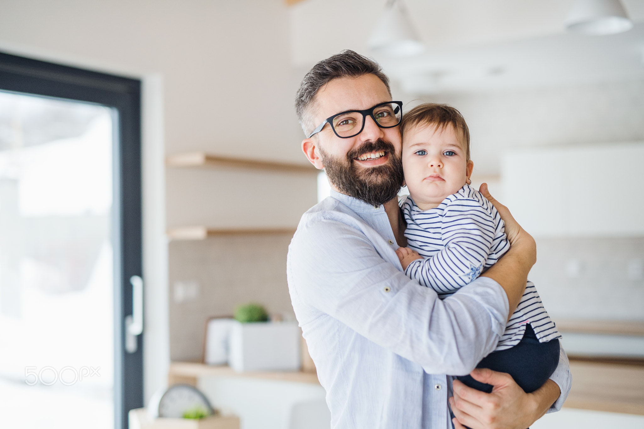 A portrait of father with a toddler girl indoors.