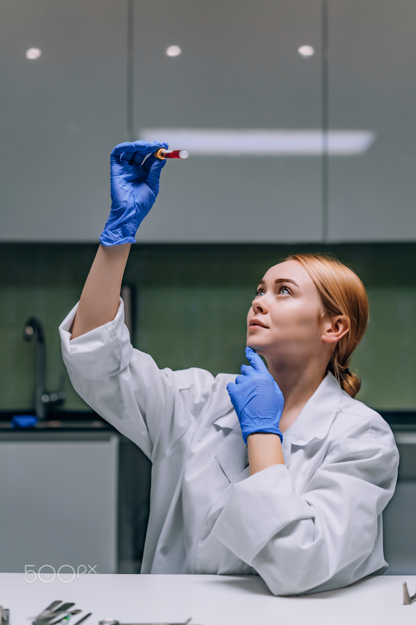 Female medical or scientific researcher looking at a test tube in a laboratory.