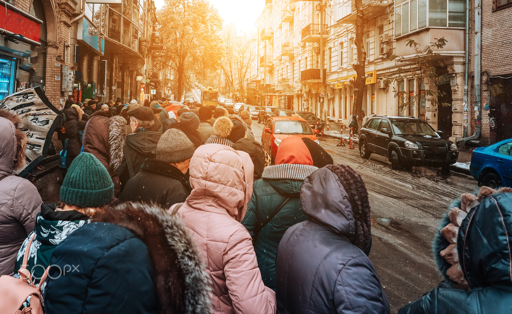 Many unidentified people are waiting for city transport at the bus stop
