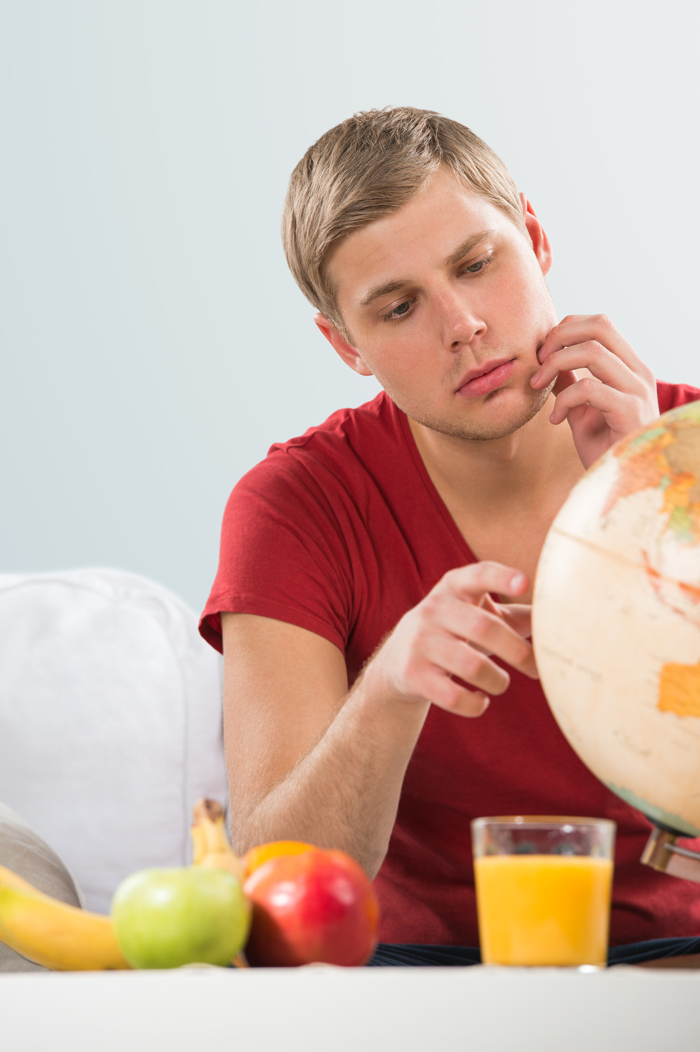 Portrait of young handsome caucasian man at home looking at glob