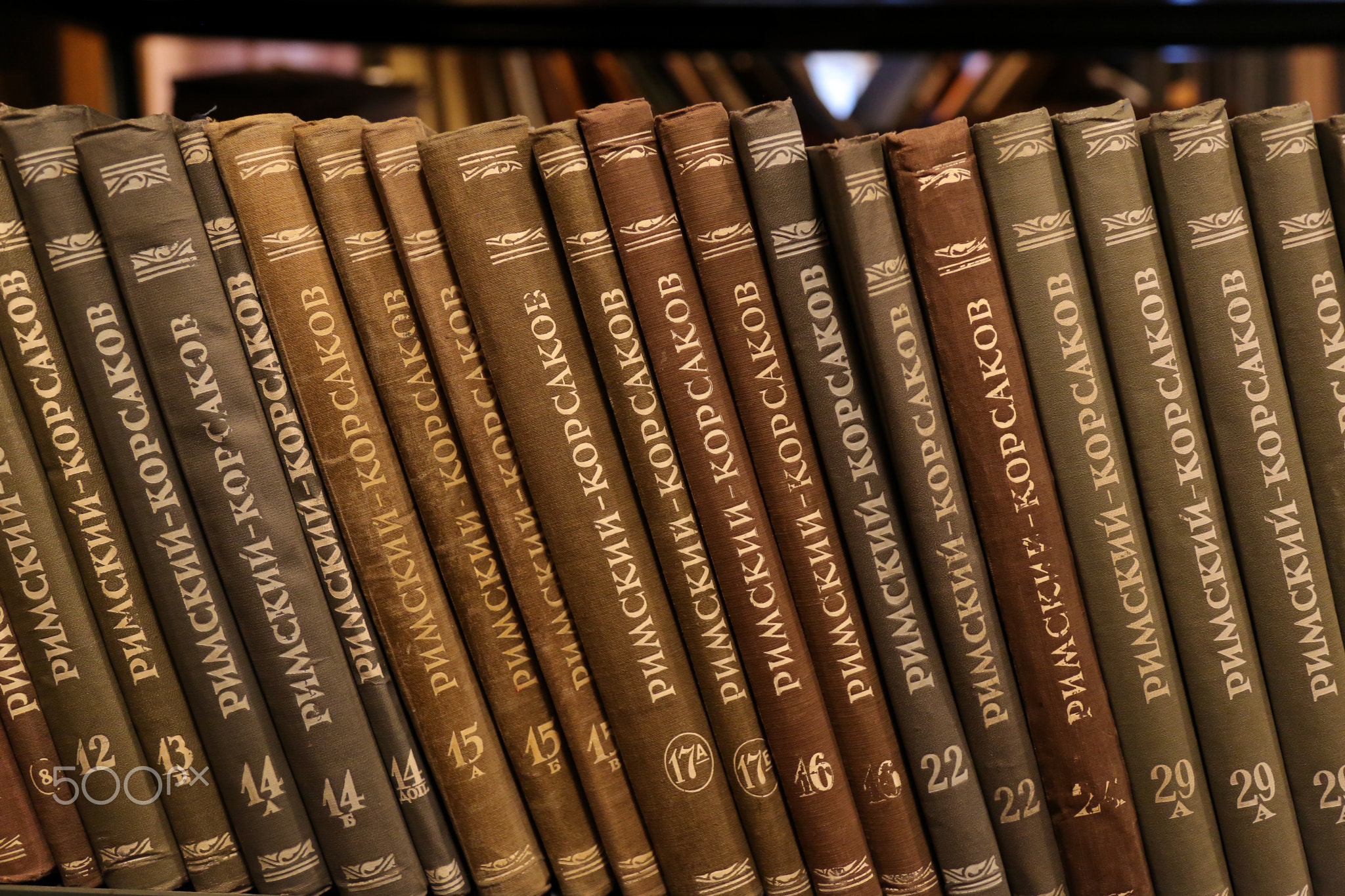 Old books on the shelf in the library. Picture taken in retro style.