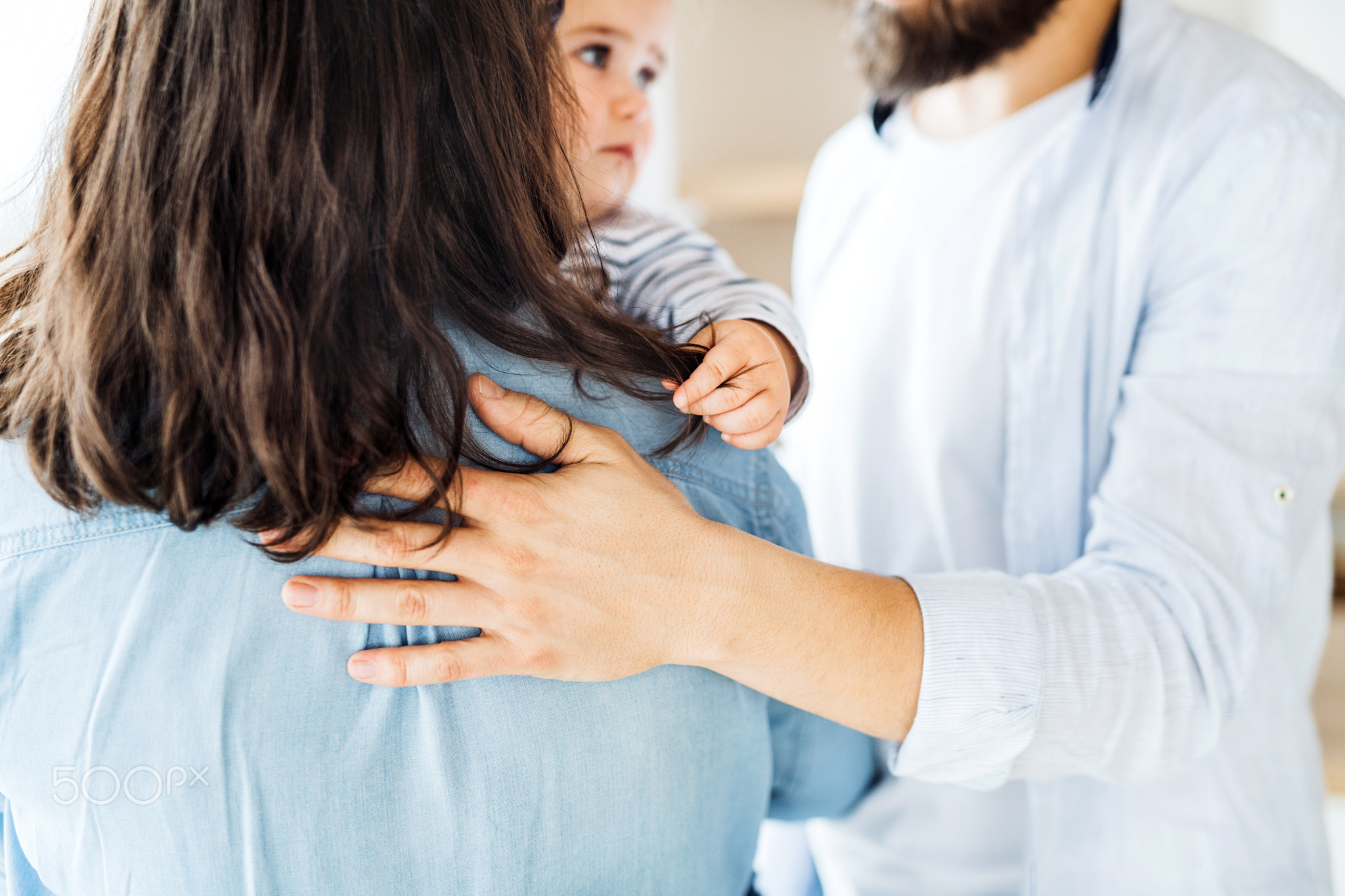 Midsection of young family with toddler girl standing indoors at home.