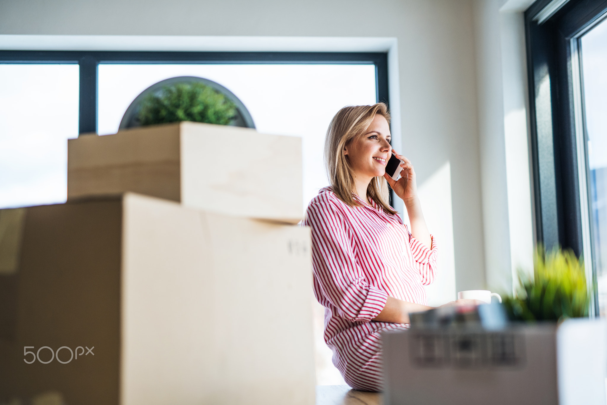 A young woman with smartphone moving in new home.