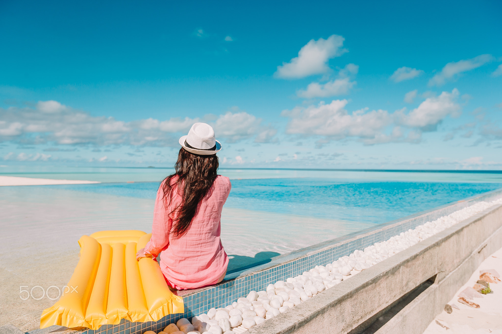 Beautiful young woman relaxing in swimming pool. Happy girl in outdoor pool at luxury hotel