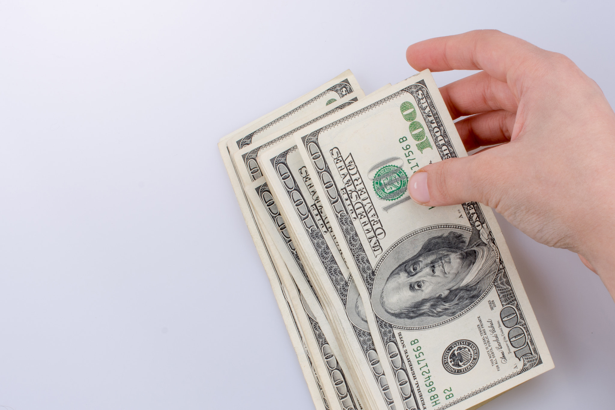 Human hand holding American dollar banknotes on white background