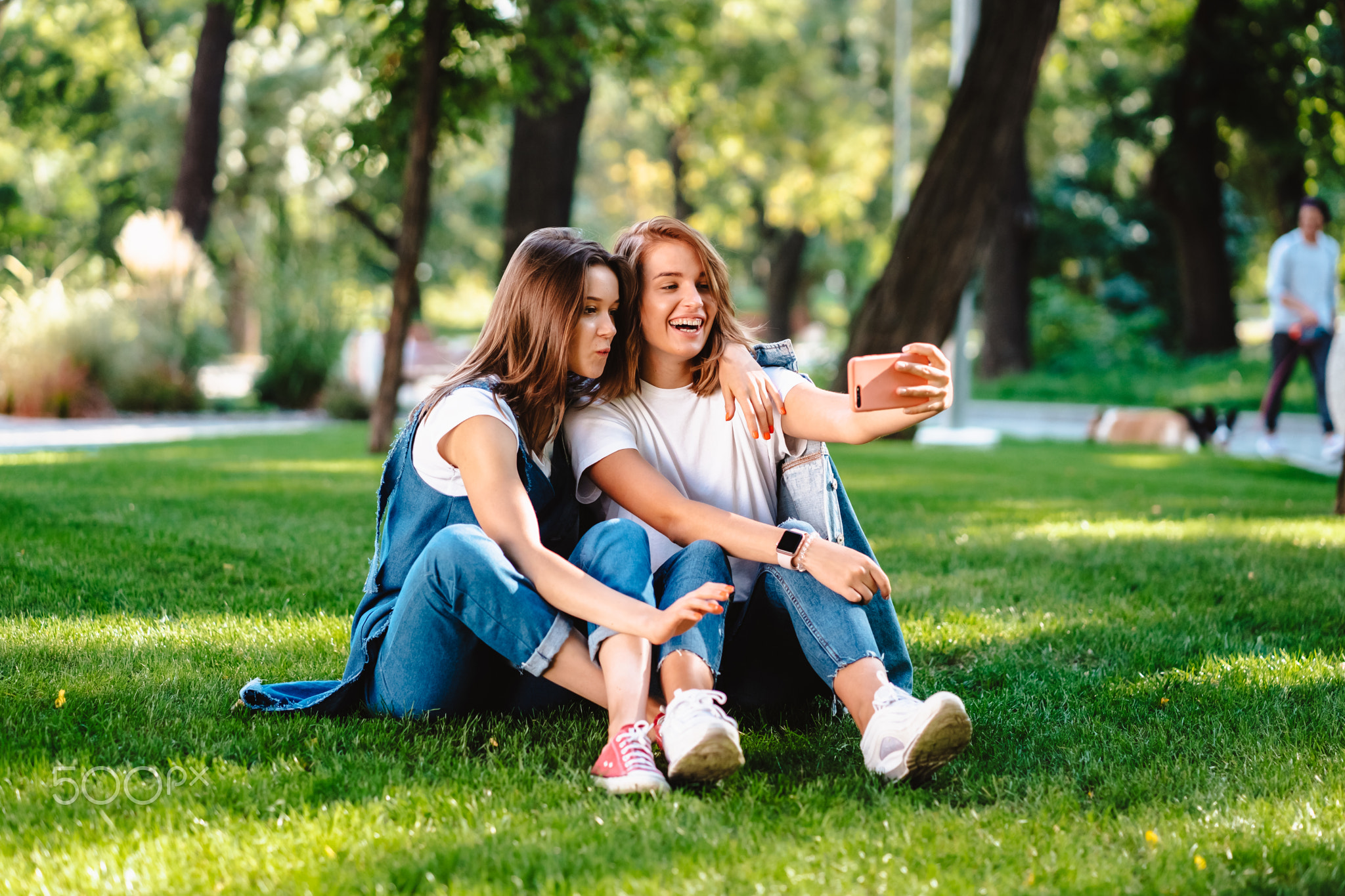 Two female friend sitting in the park have a rest take a selfie