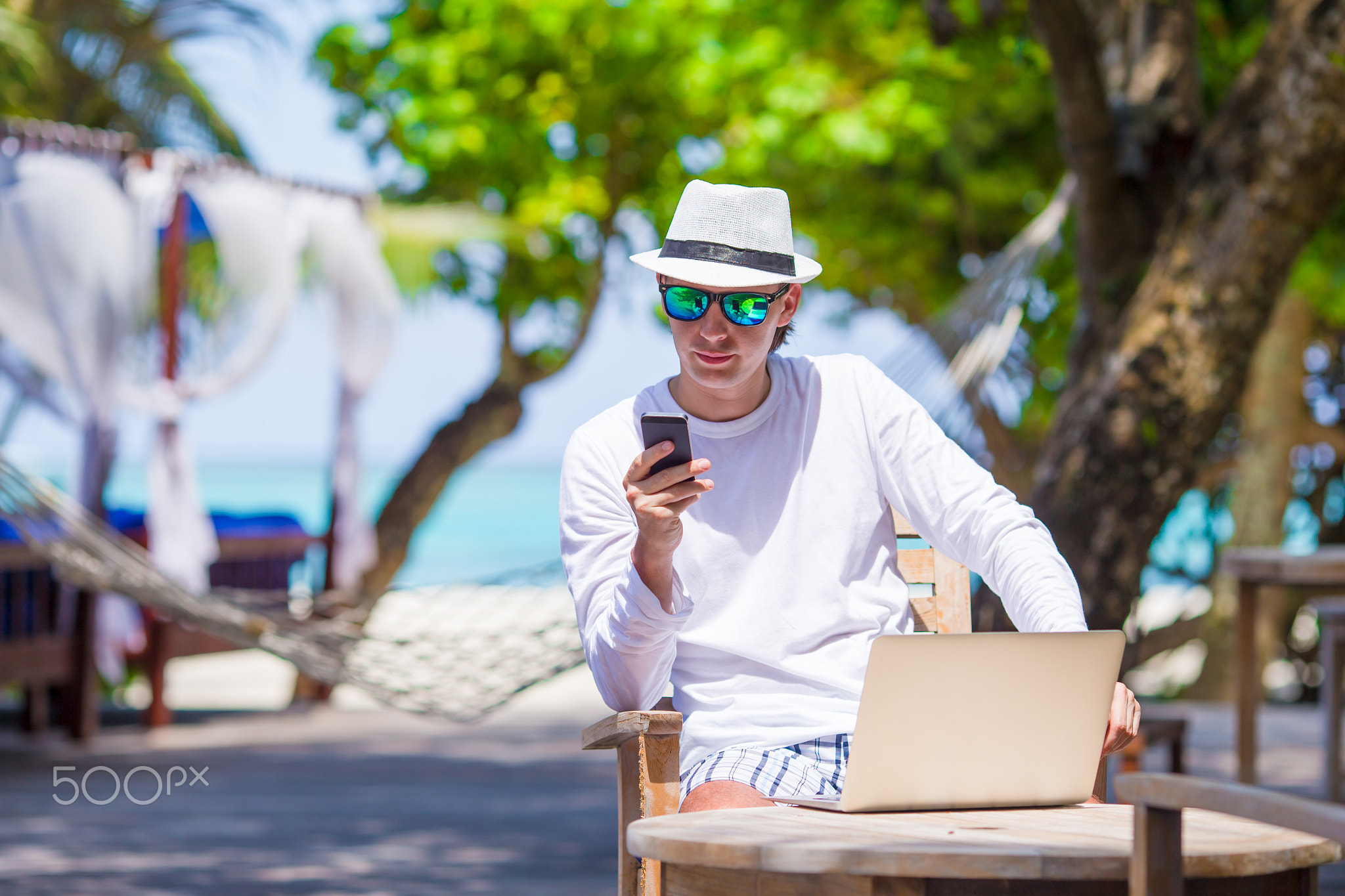 Young man with cell phone in outdoor cafe