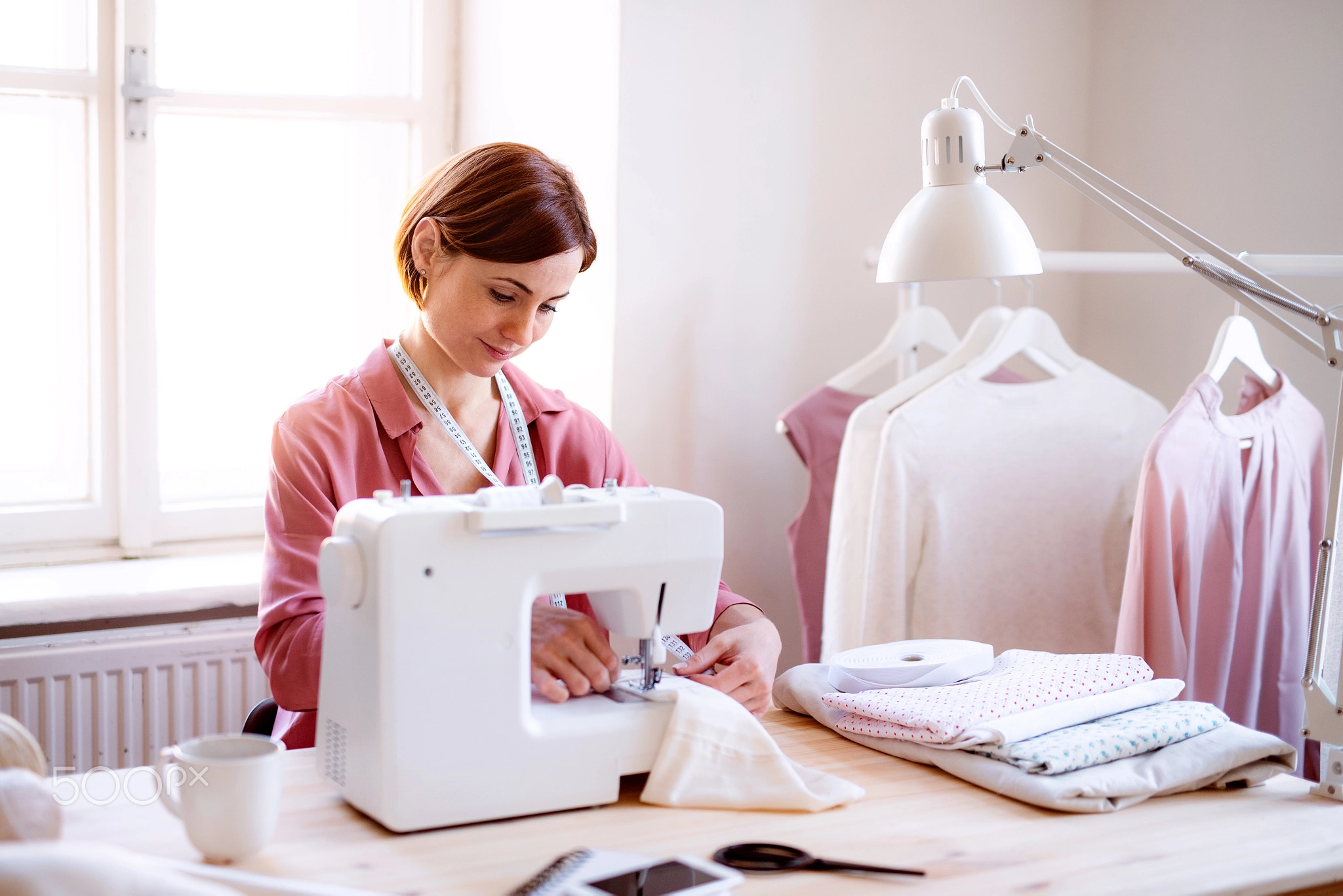 Young creative woman in a studio, working. A startup of tailoring business.