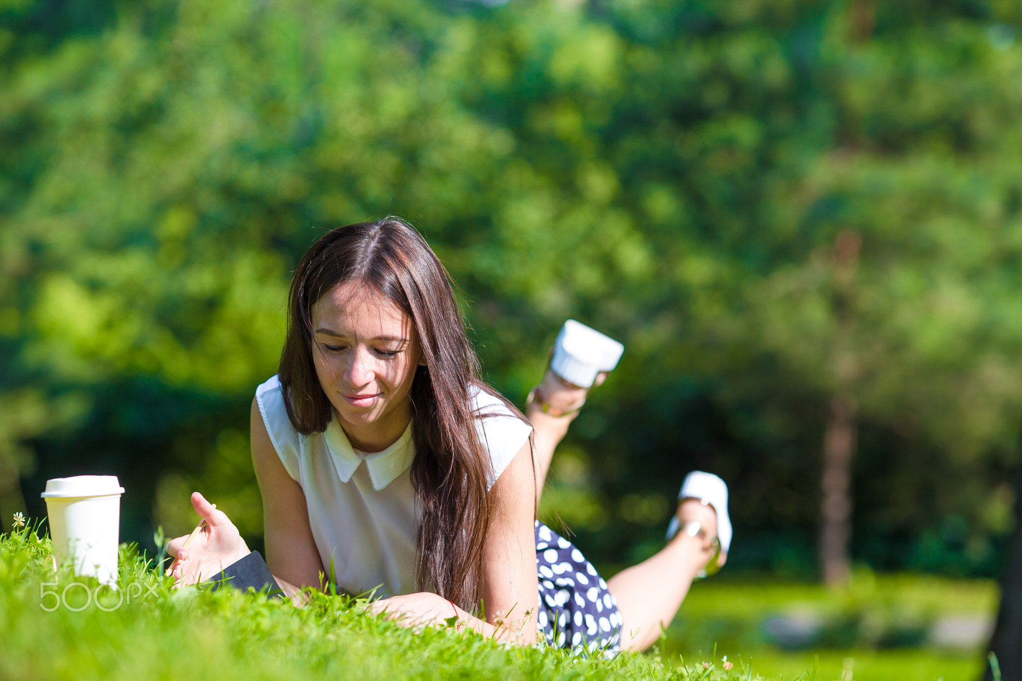 Young girl writing in her notebook outside at park