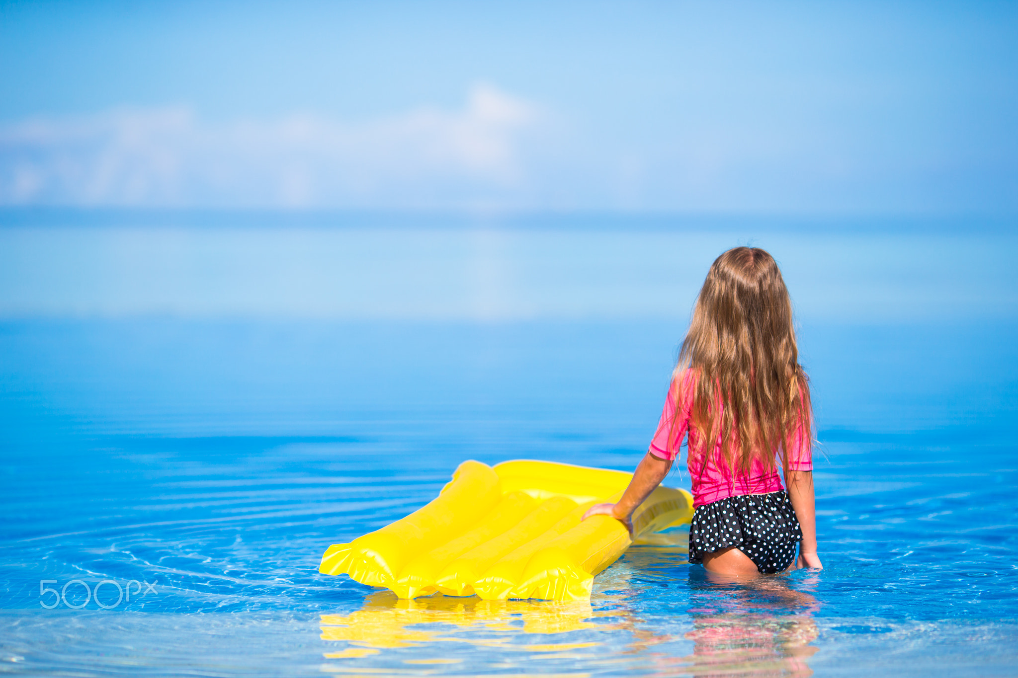 Adorable girl with inflatable air mattress in outdoor swimming pool