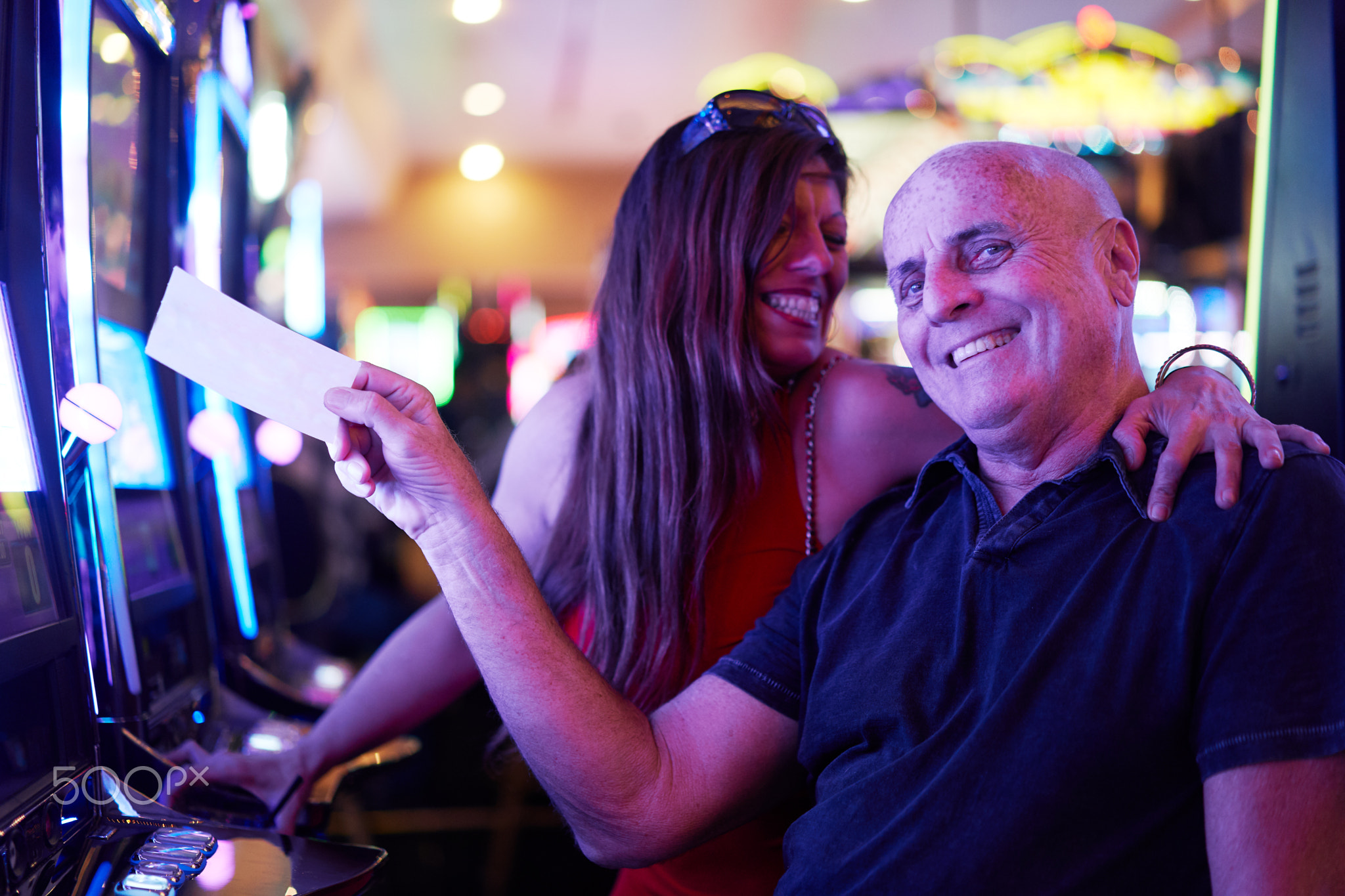 happy mature couple with payout ticket at casino