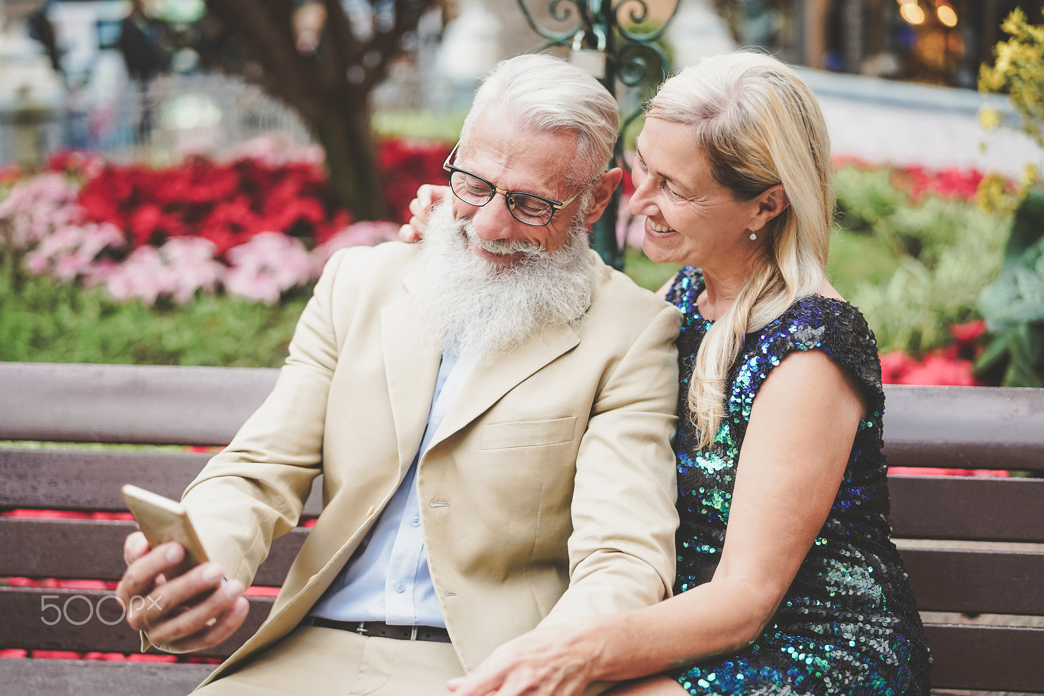 Happy senior couple watching on mobile smartphone outdoor