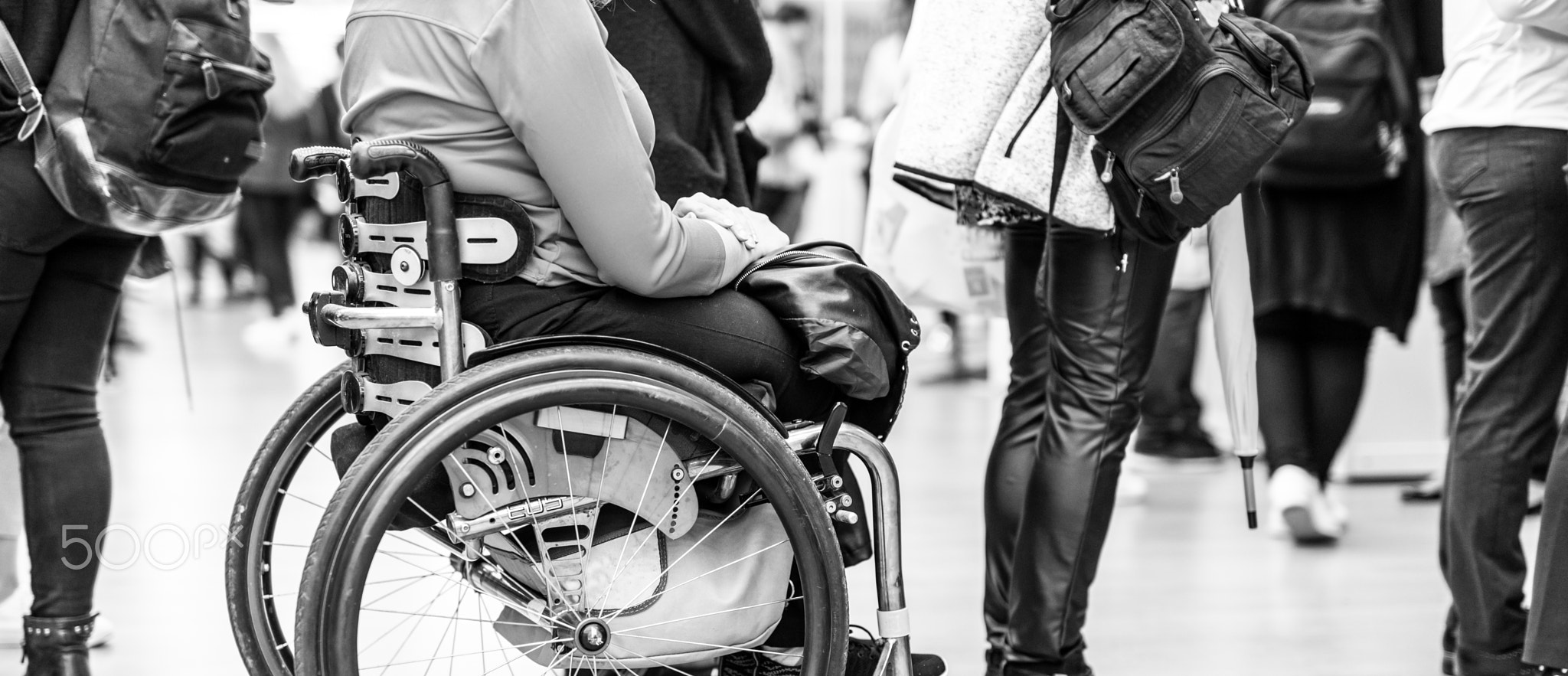 Close up of unrecognizable hanicapped woman on a wheelchair queuing in line to perform everyday...