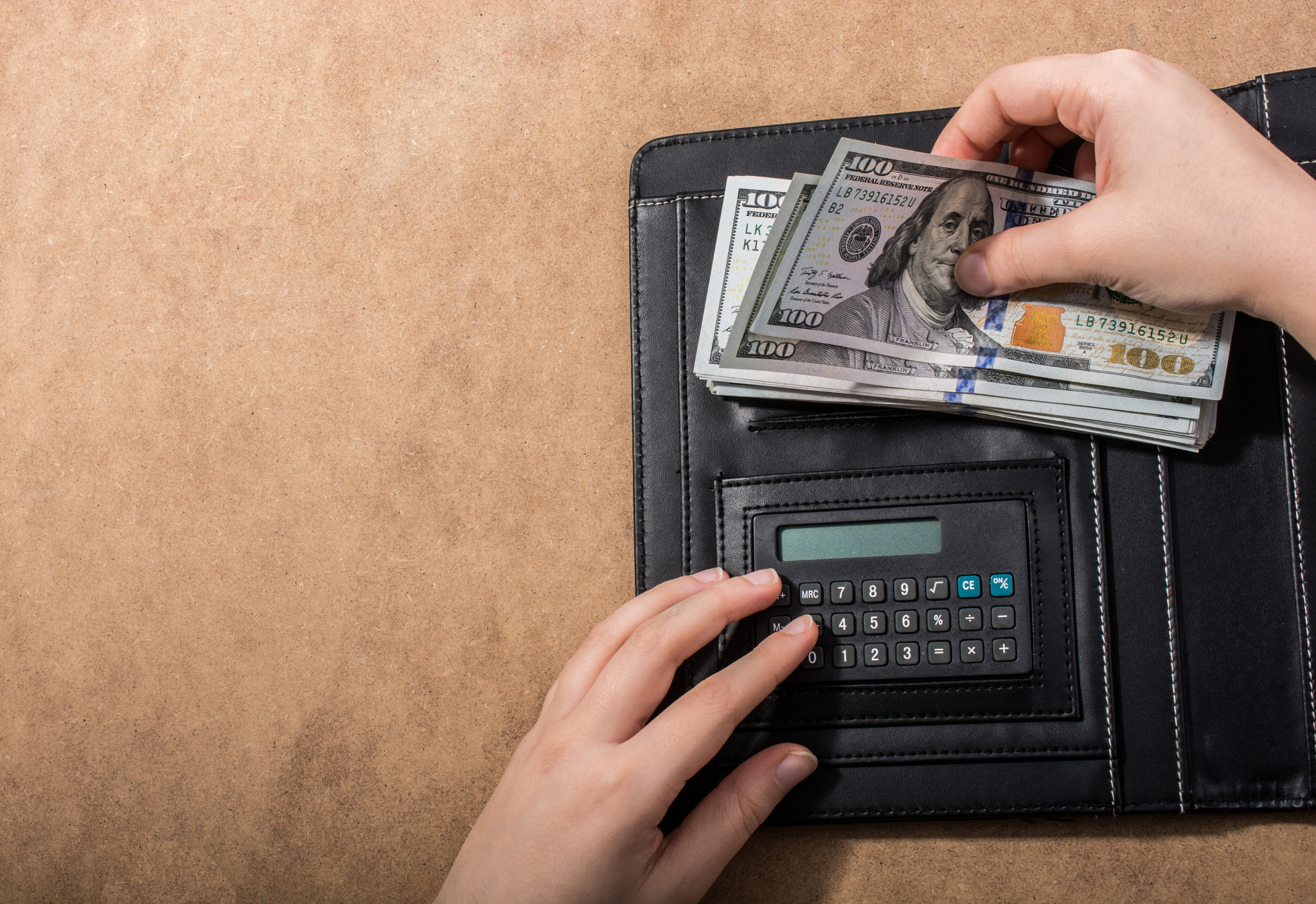 Hand holding American dollar banknotes by the calculator