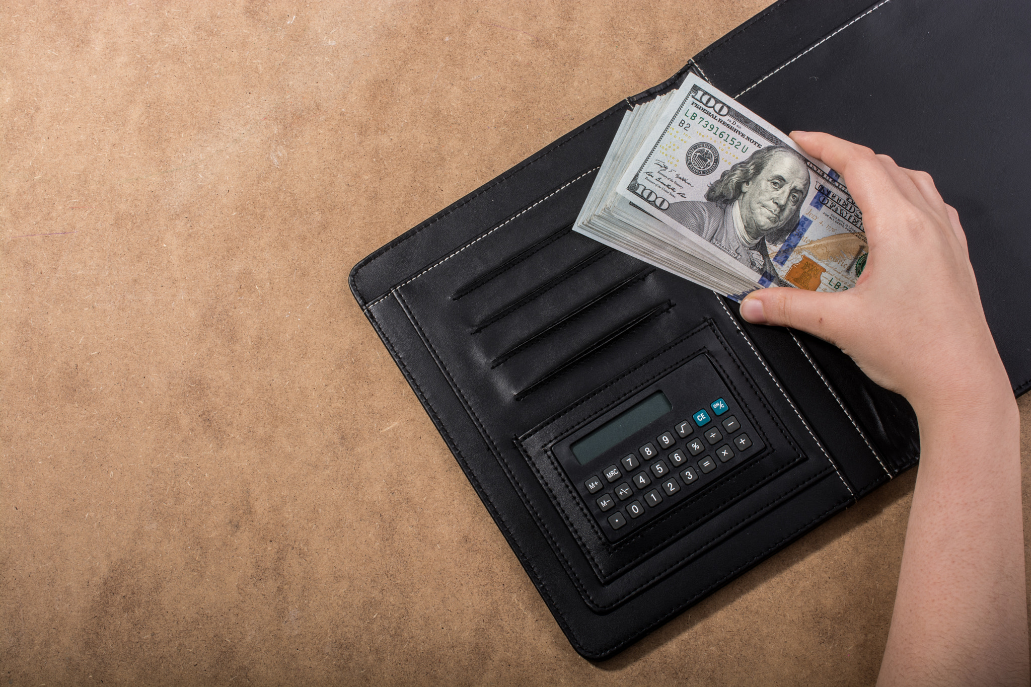 Hand holding American dollar isolated on wooden background