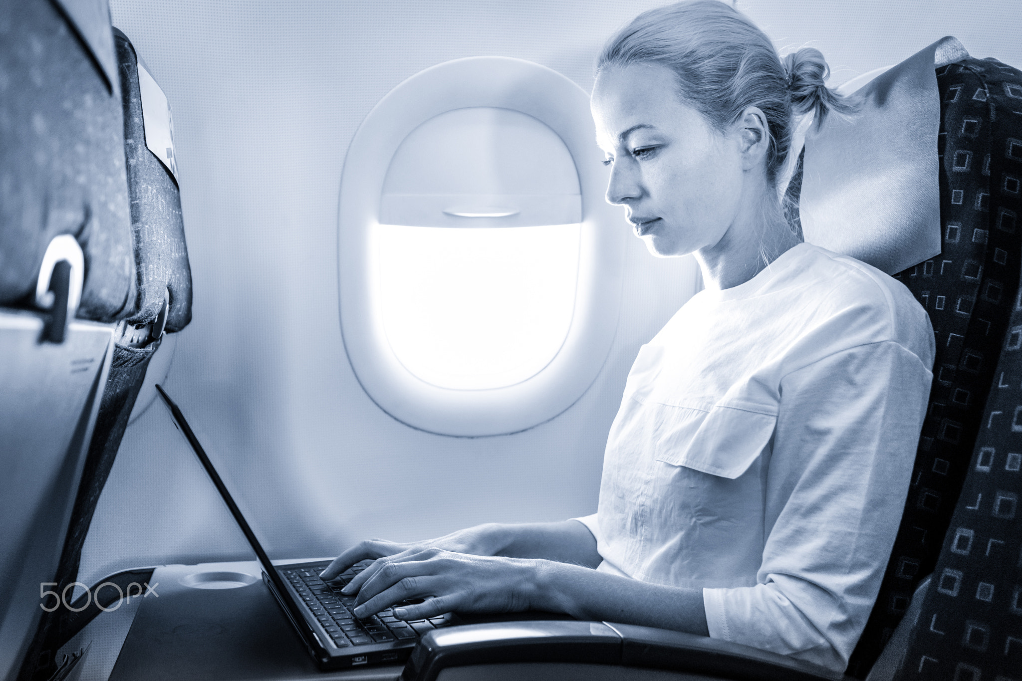 Attractive caucasian female passenger working at modern laptop computer using wireless connection...