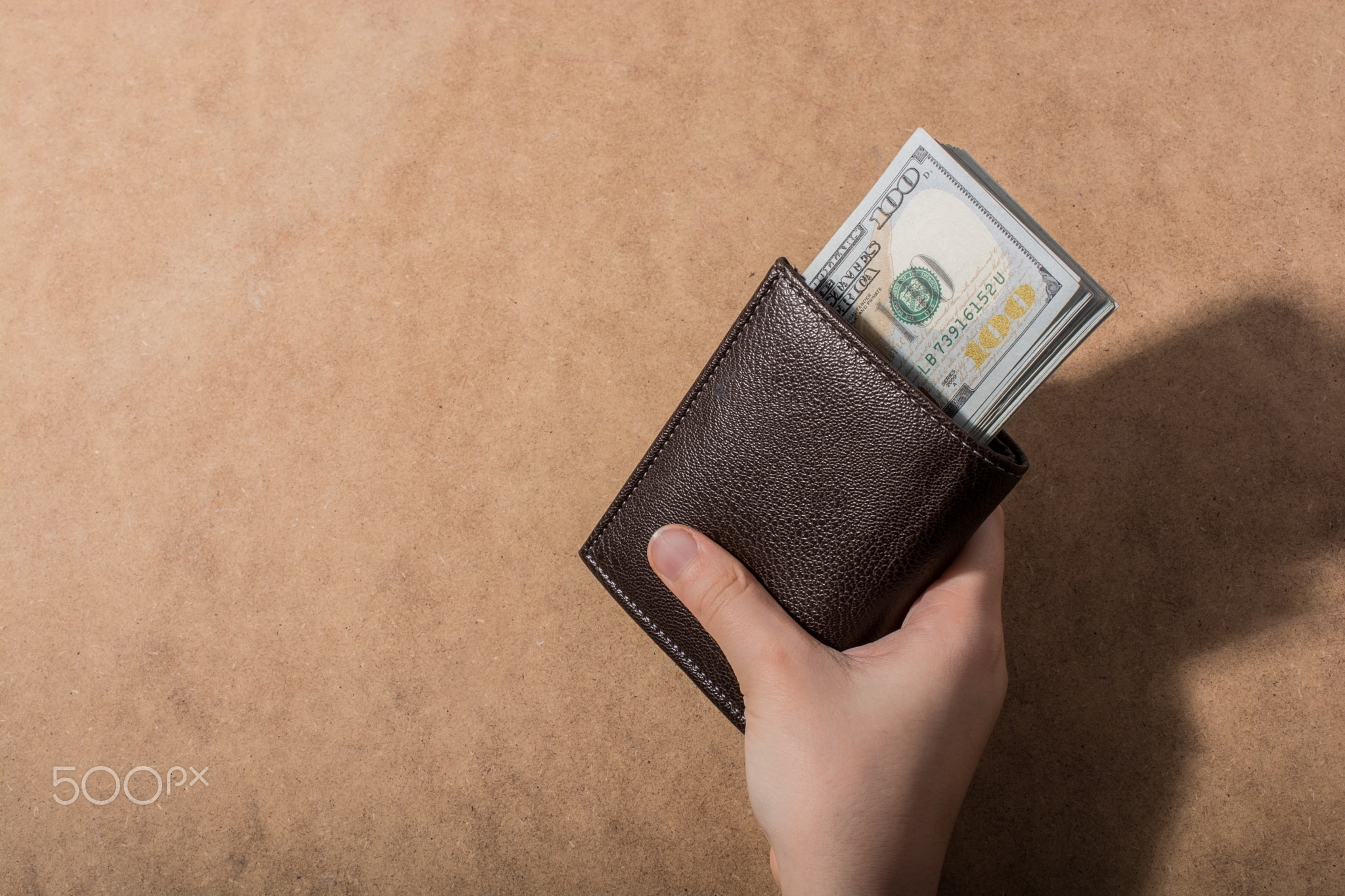 Hand holding American dollar isolated on wooden background