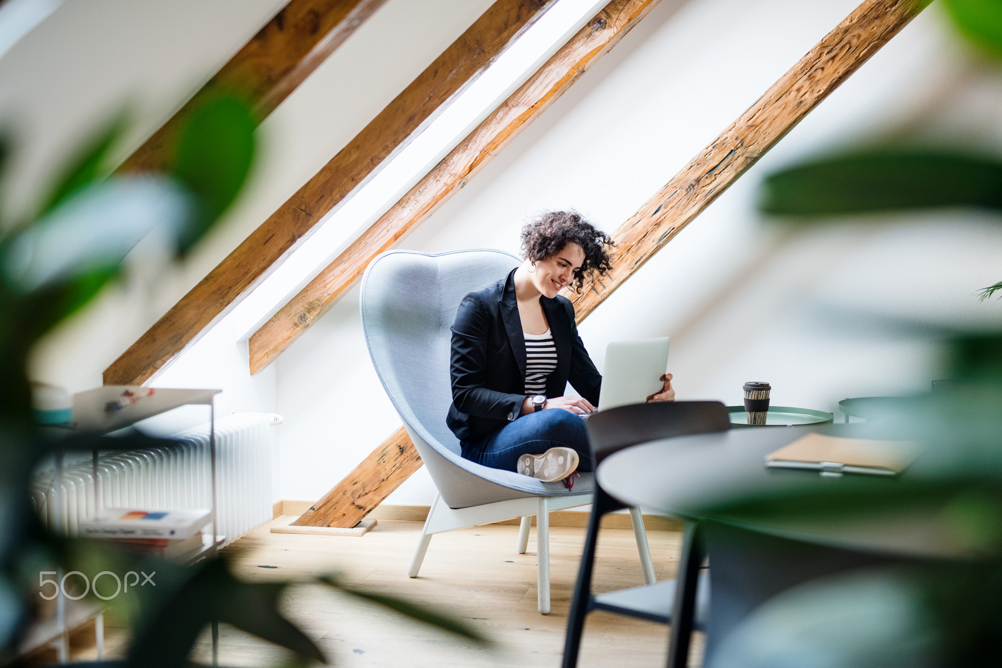 Young businesswoman with laptop sitting at the table in office, working.