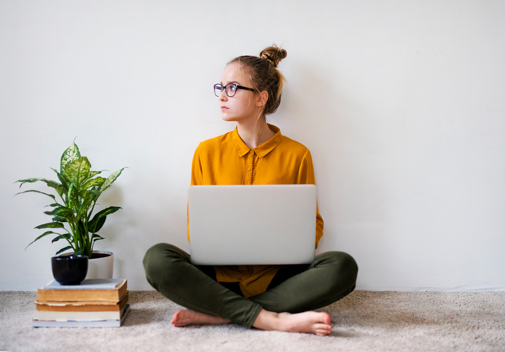 A young female student sitting on floor using laptop when studying. by Jozef Polc on 500px.com