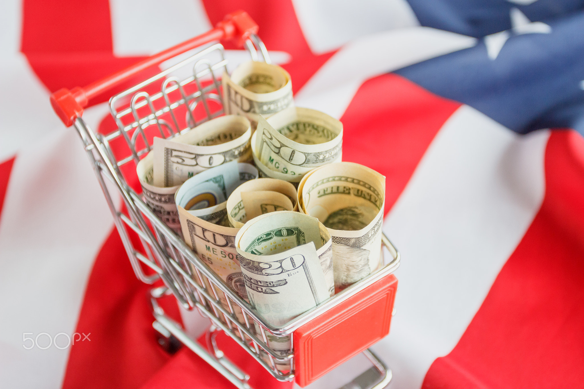 Shopping cart with American dollars inside on the national flag of United States of America