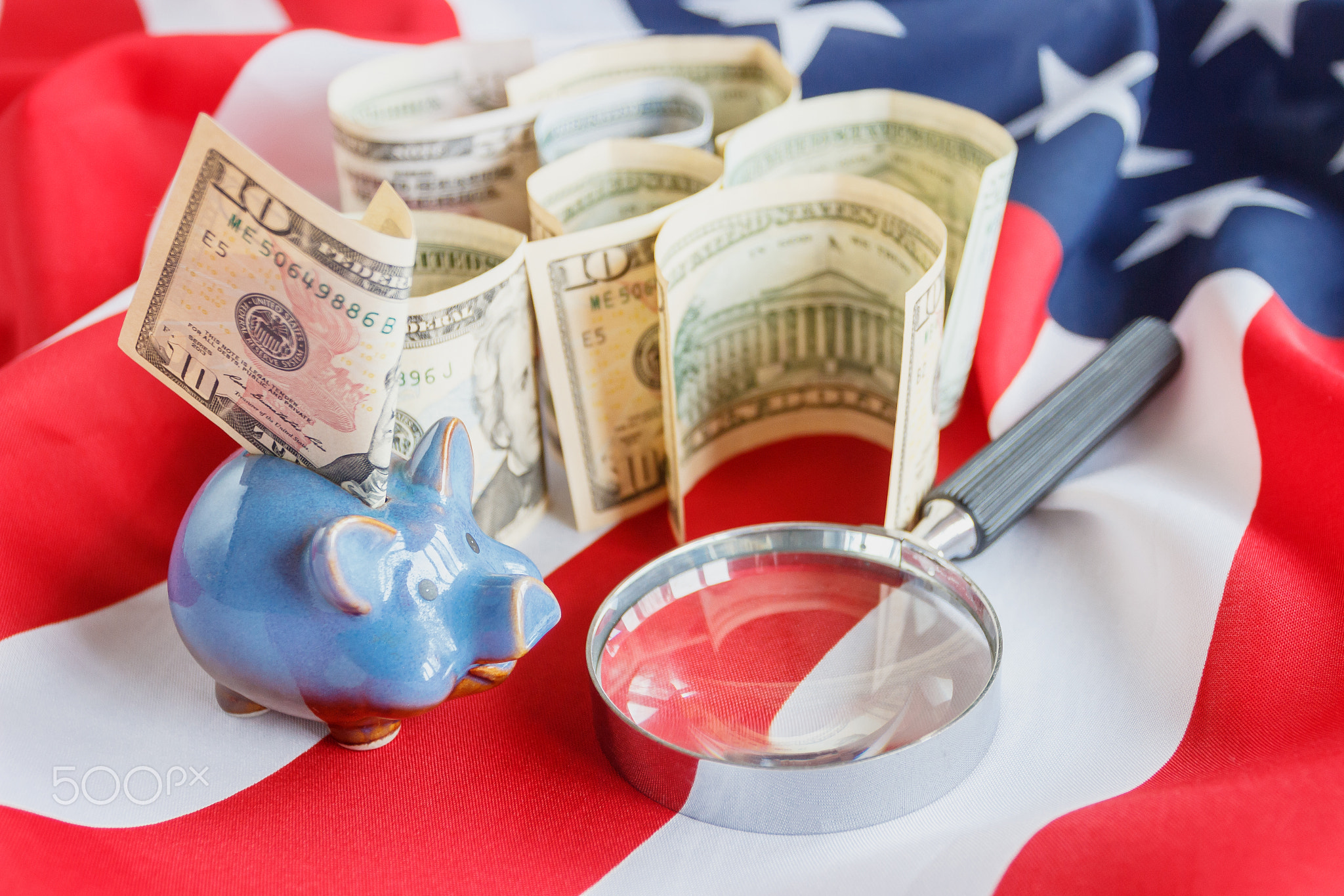 Magnifying glass and American dollars on the national flag of United States of America, background