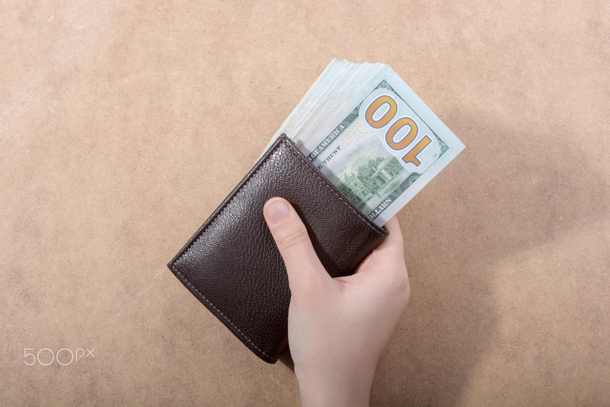 Hand holding American dollar isolated on wooden background