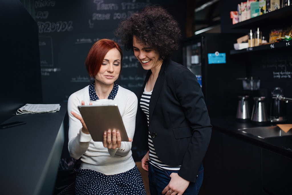 Two young businesspeople using tablet in office, start-up concept. by Jozef Polc on 500px.com