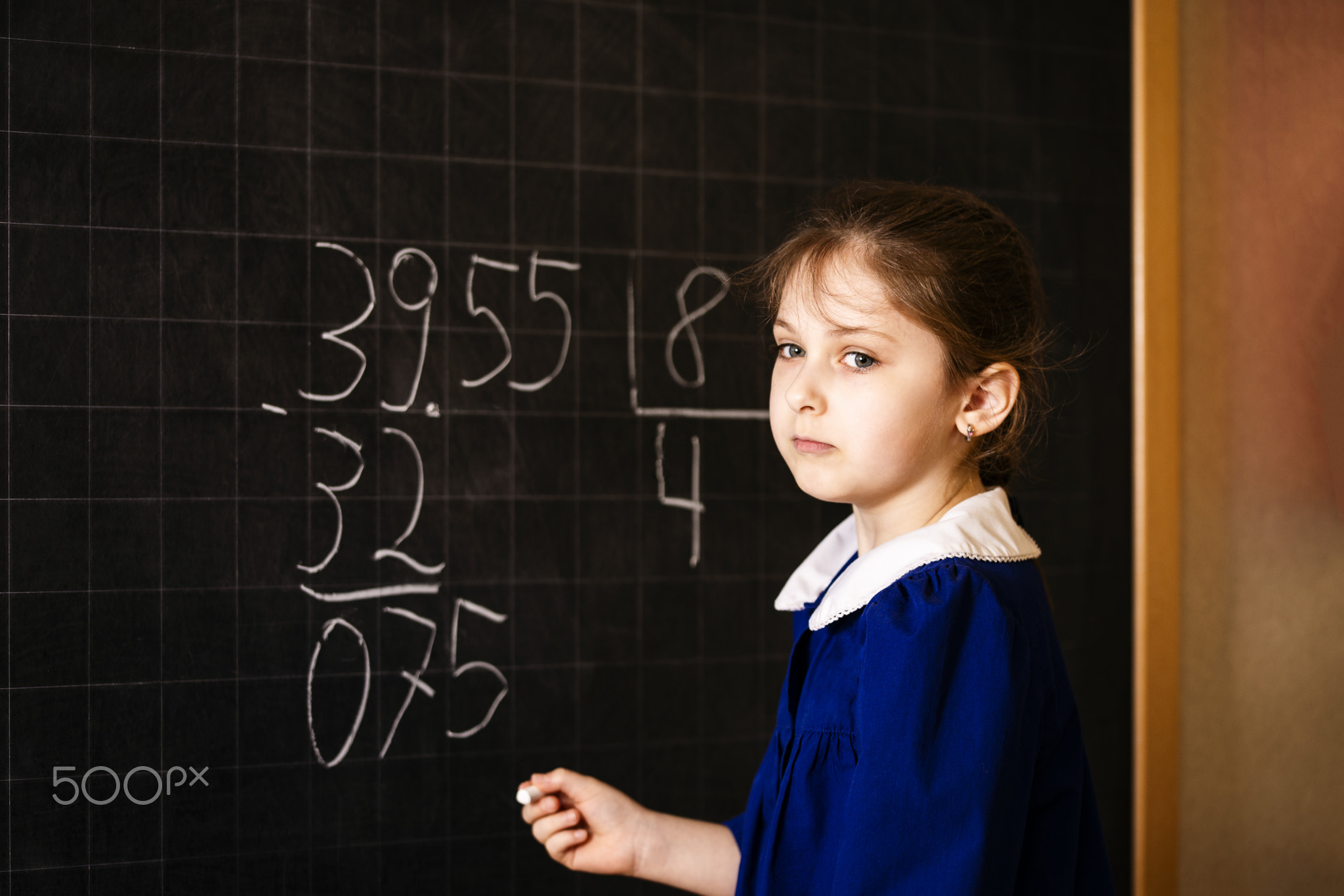 Italian elementary school girl trying to solve a mathematics examples, making a long division at...