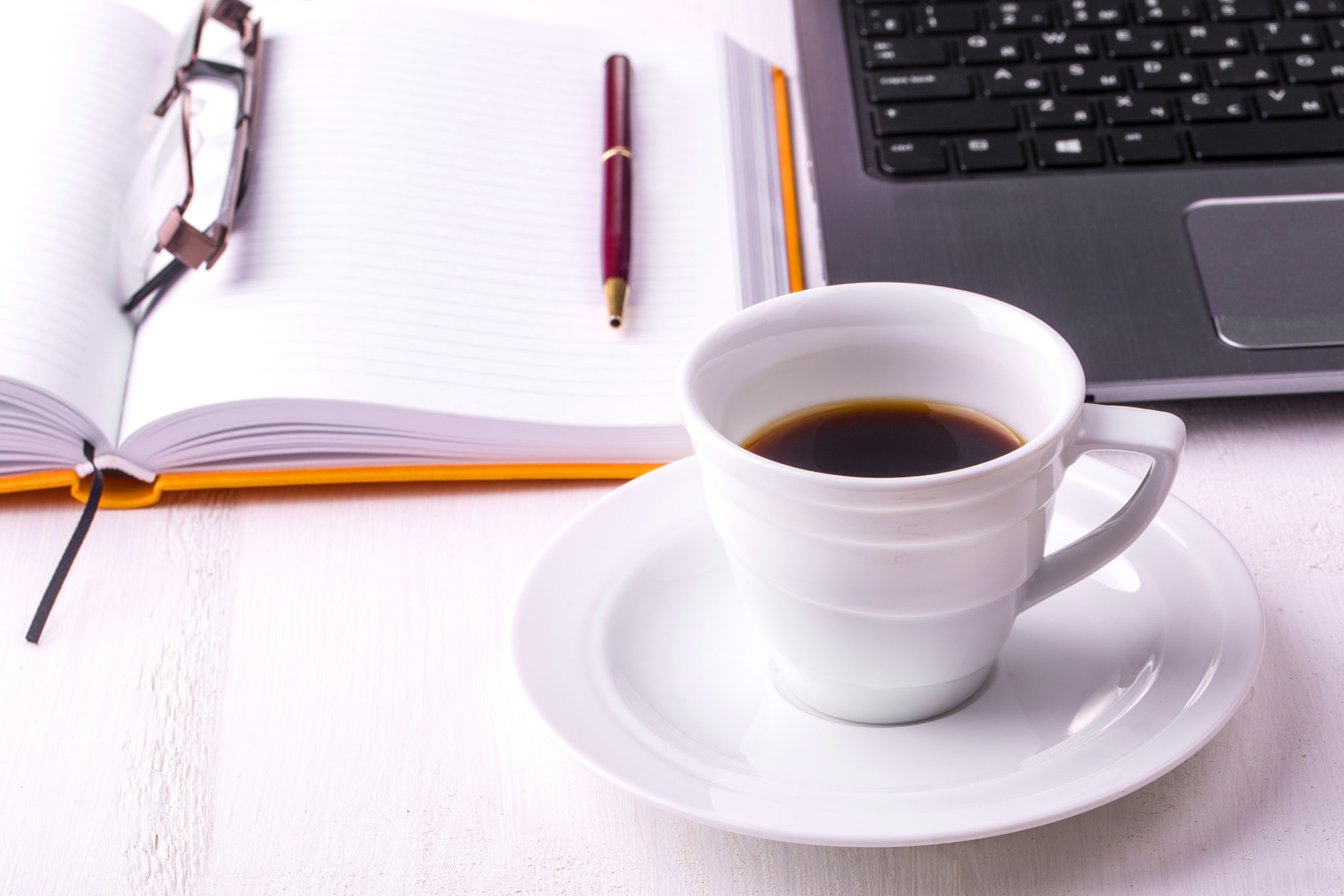 laptop, notebook with a cup of coffee and a pencil