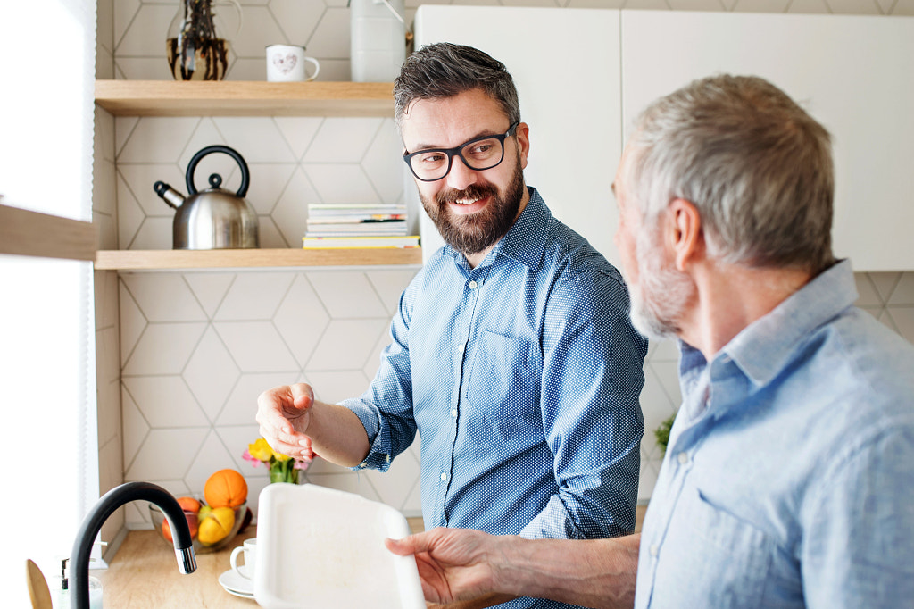 Adult hipster son and senior father indoors in kitchen at home, washing dishes. by Jozef Polc on 500px.com