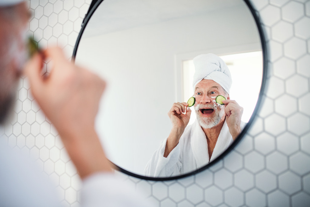 A senior man with cucumber on eyes indoors at home. Copy space. by Jozef Polc on 500px.com