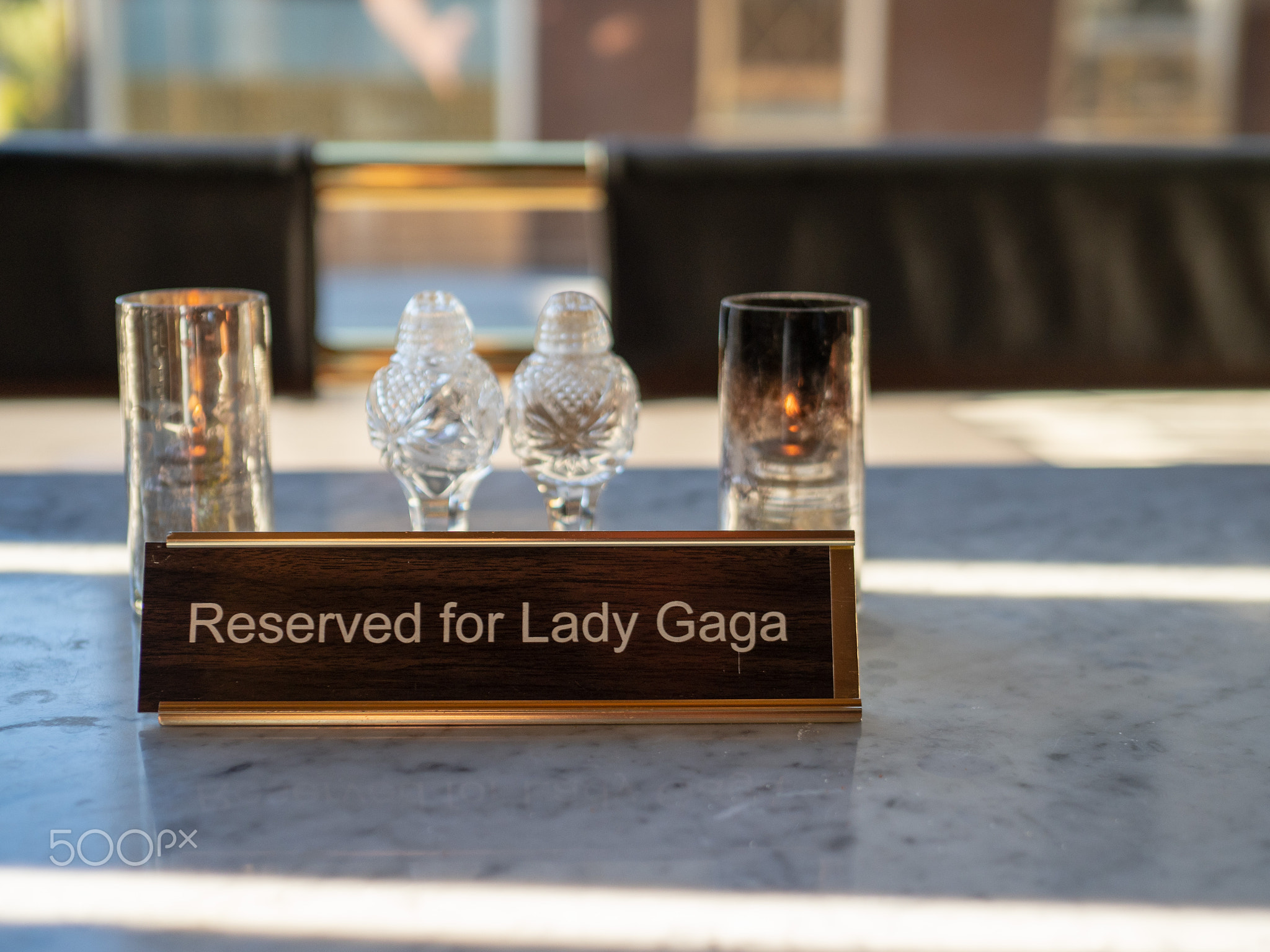 Reserved for Lady Gaga sign sitting on marble restaurant table with candles with salt and pepper...