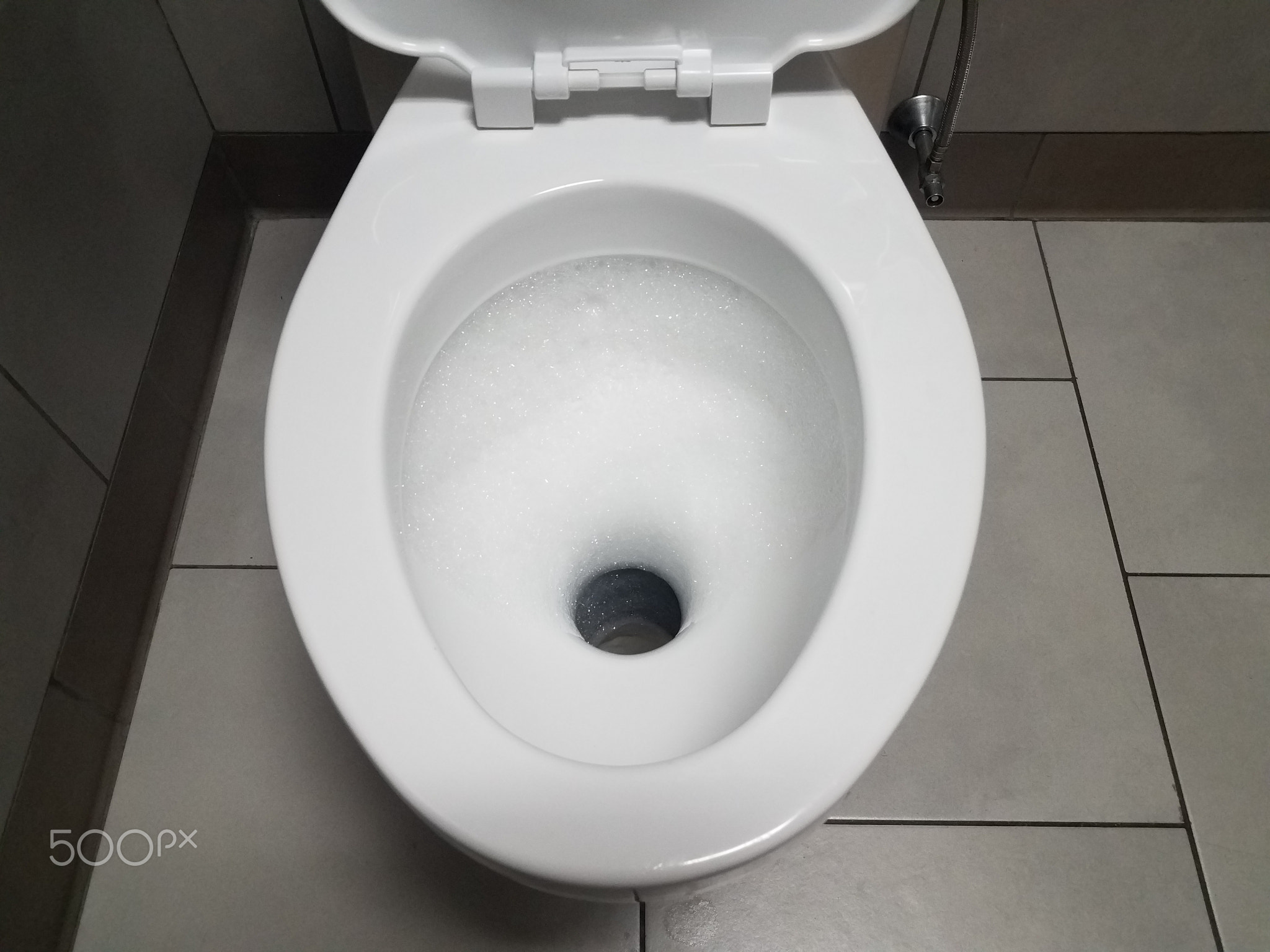white toilet with bubbles in restroom or bathroom