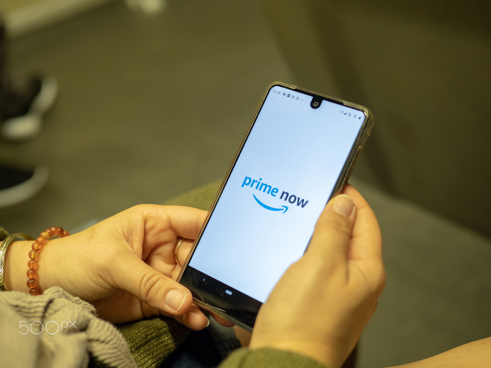 Woman opening Amazon Prime Now app on Android device screen while commuting on subway train