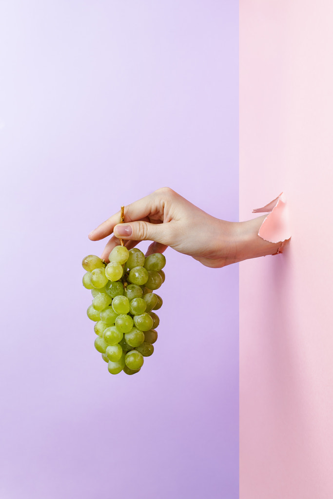 Woman's hand holding ripe green grape through pastel torn paper by Nataly Lavrenkova on 500px.com