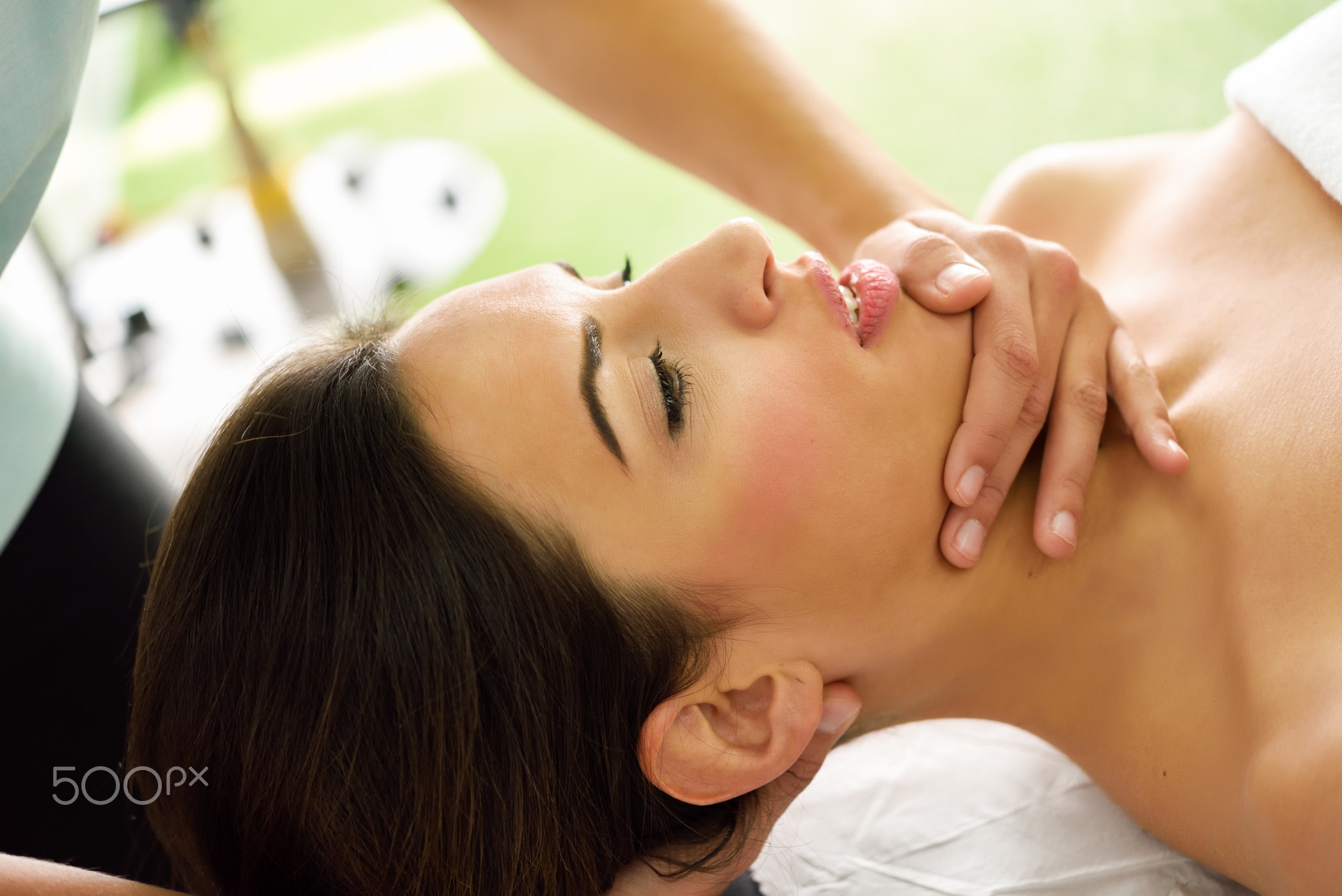 Young woman receiving a head massage in a spa center.