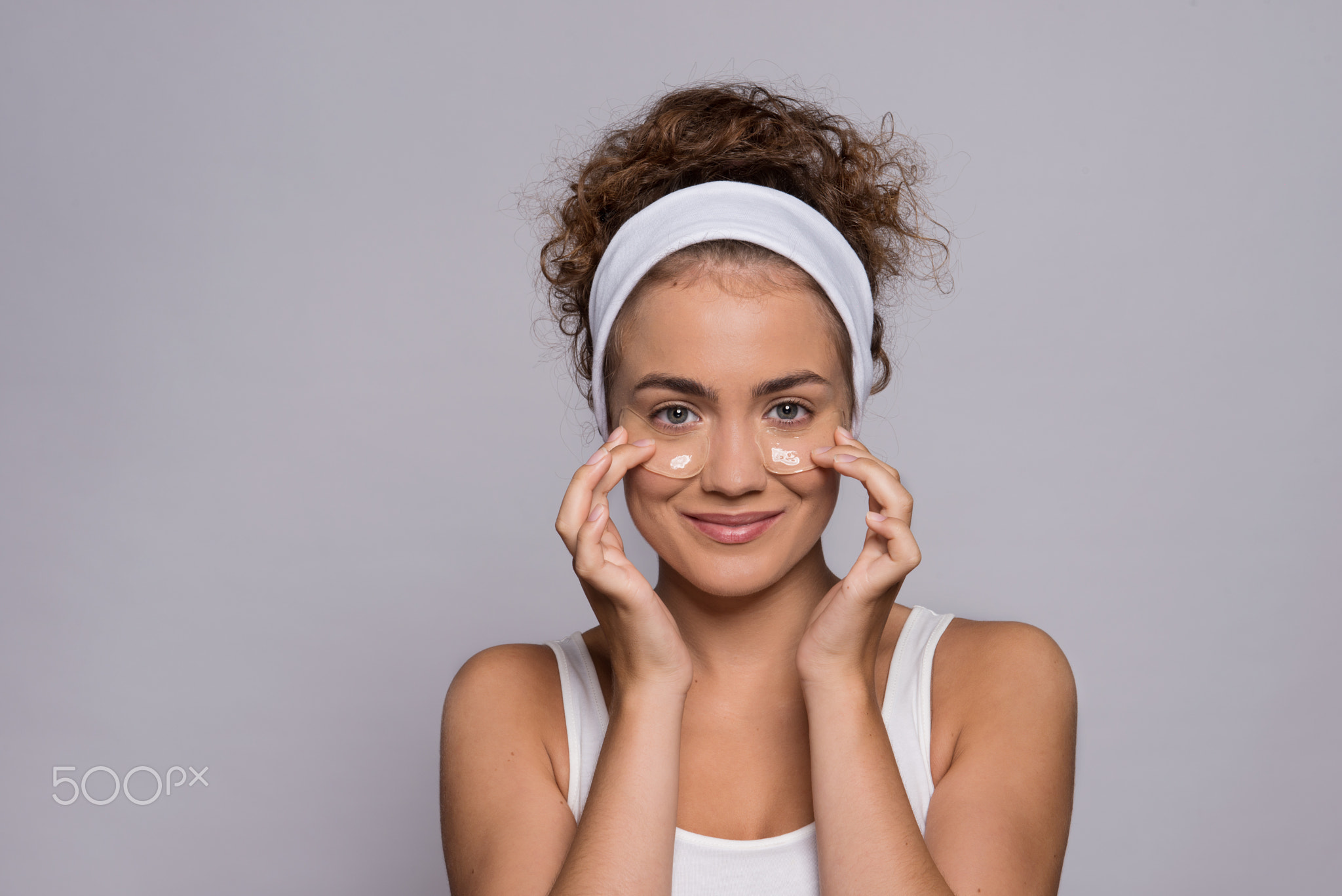 A portrait of a young woman with collagen pads in a studio, beauty and skin care.